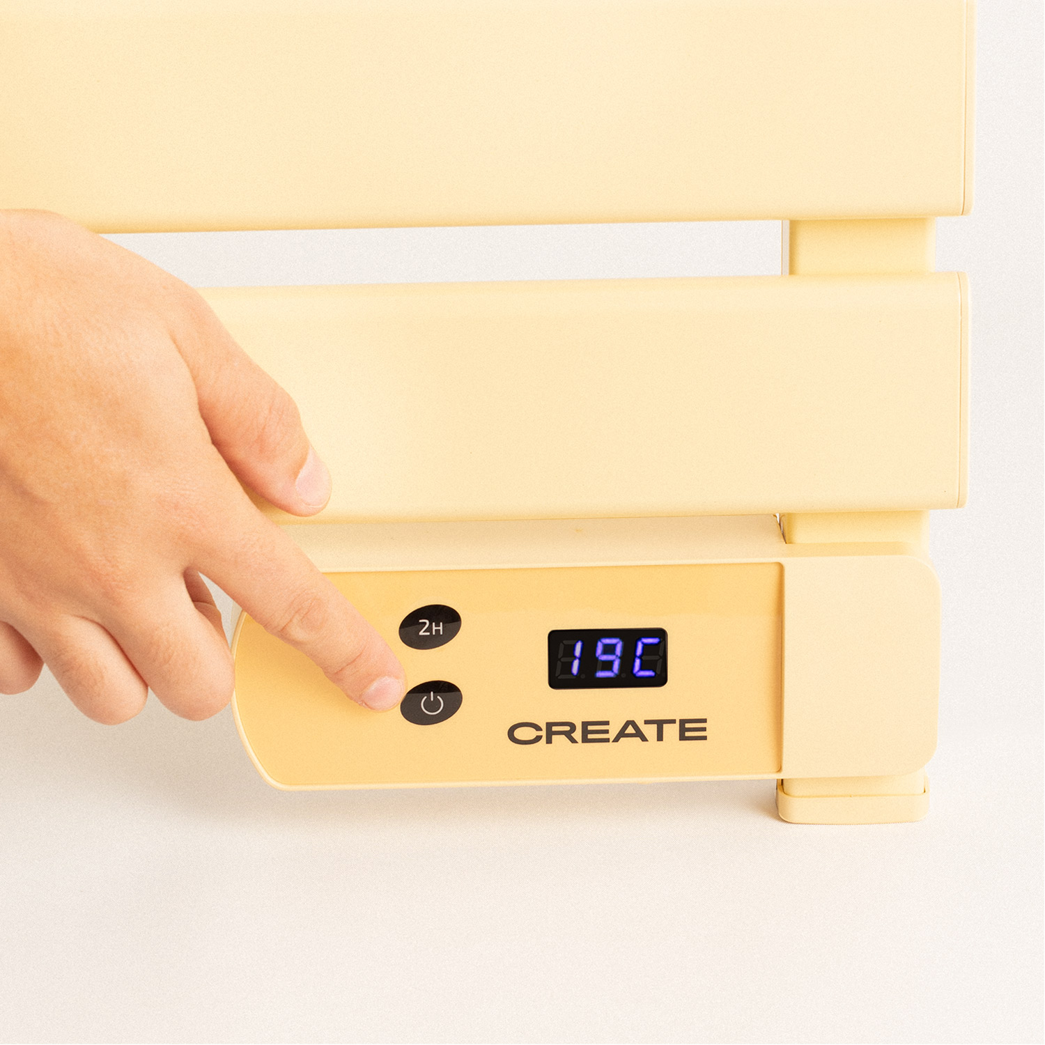 El dedo de una persona presiona un botón en un calentador amarillo. La pantalla muestra 19°C.