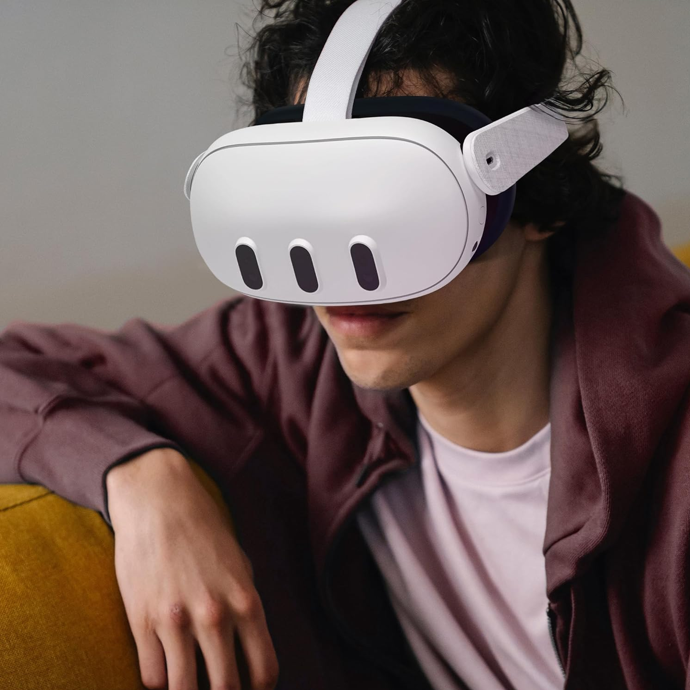 Mann mit VR-Headset, weiß und grau, im Raum, trägt einen weinroten Kapuzenpullover.