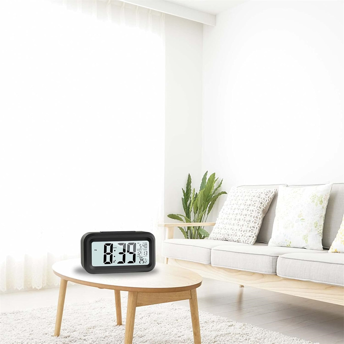 Schwarze Digitaluhr auf einem Holztisch. Zeigt Zeit, Datum und Temperatur.
