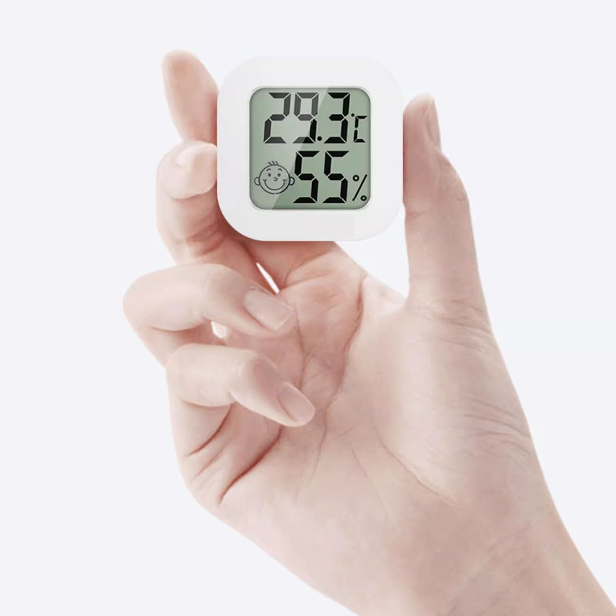 Hand hält ein kleines digitales Thermometer, zeigt Temperatur- und Feuchtigkeitswerte.