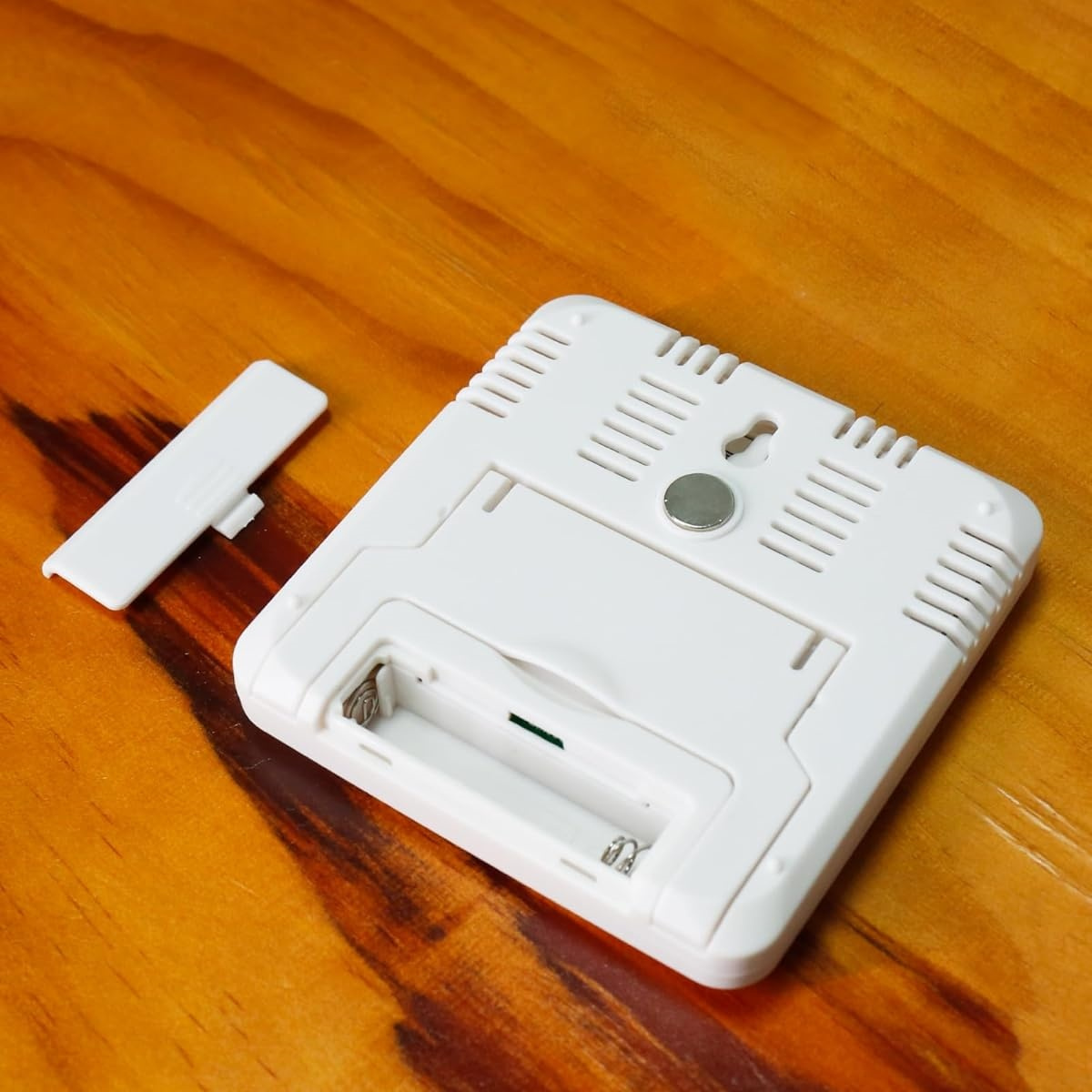 Ein weißes batteriebetriebenes Gerät. Das Gerät befindet sich auf einer Holzoberfläche. Der Hintergrund ist ein Holztisch.