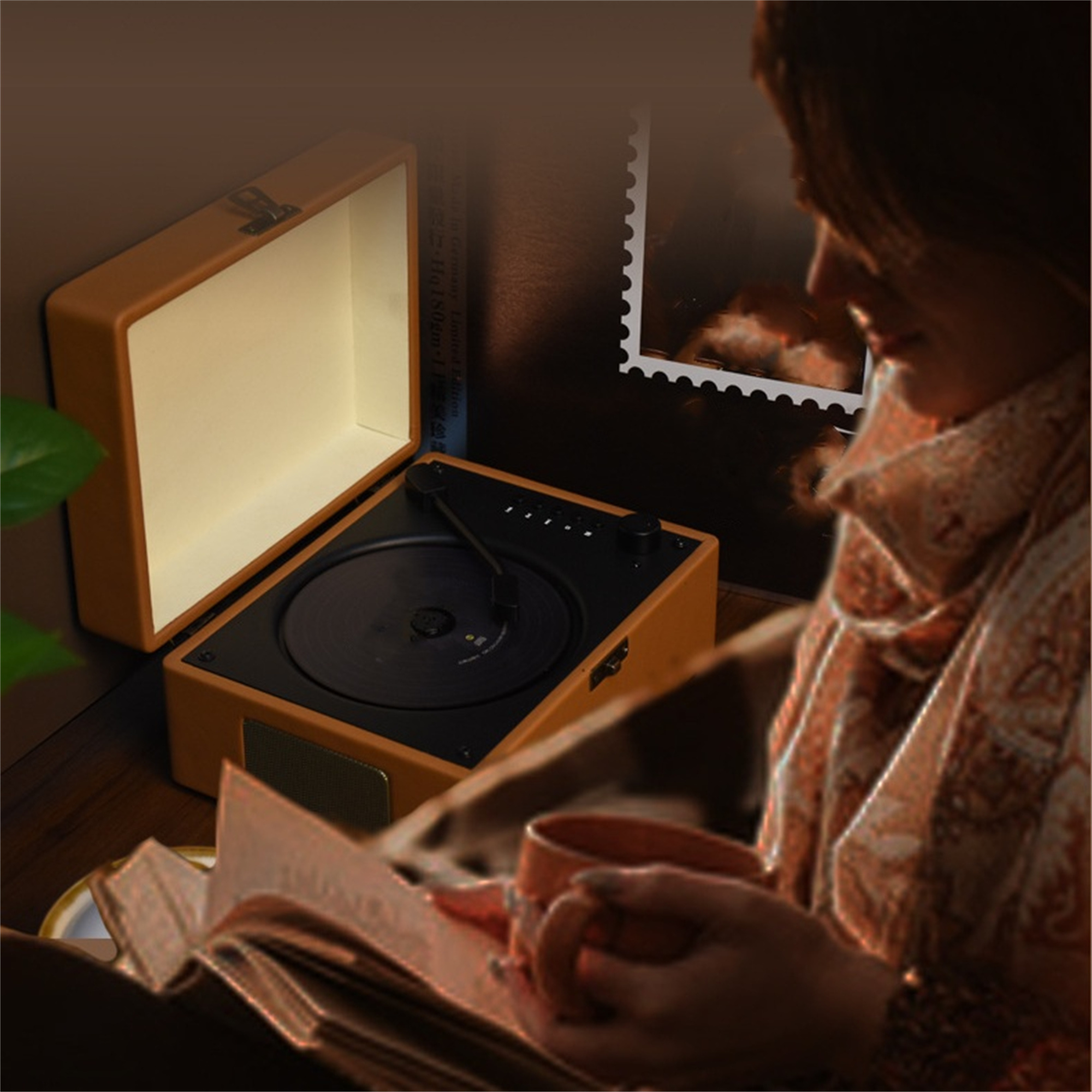 Vintage Plattenspieler mit offenem Deckel, eine Frau liest ein Buch und hält eine Tasse in einem Raum.