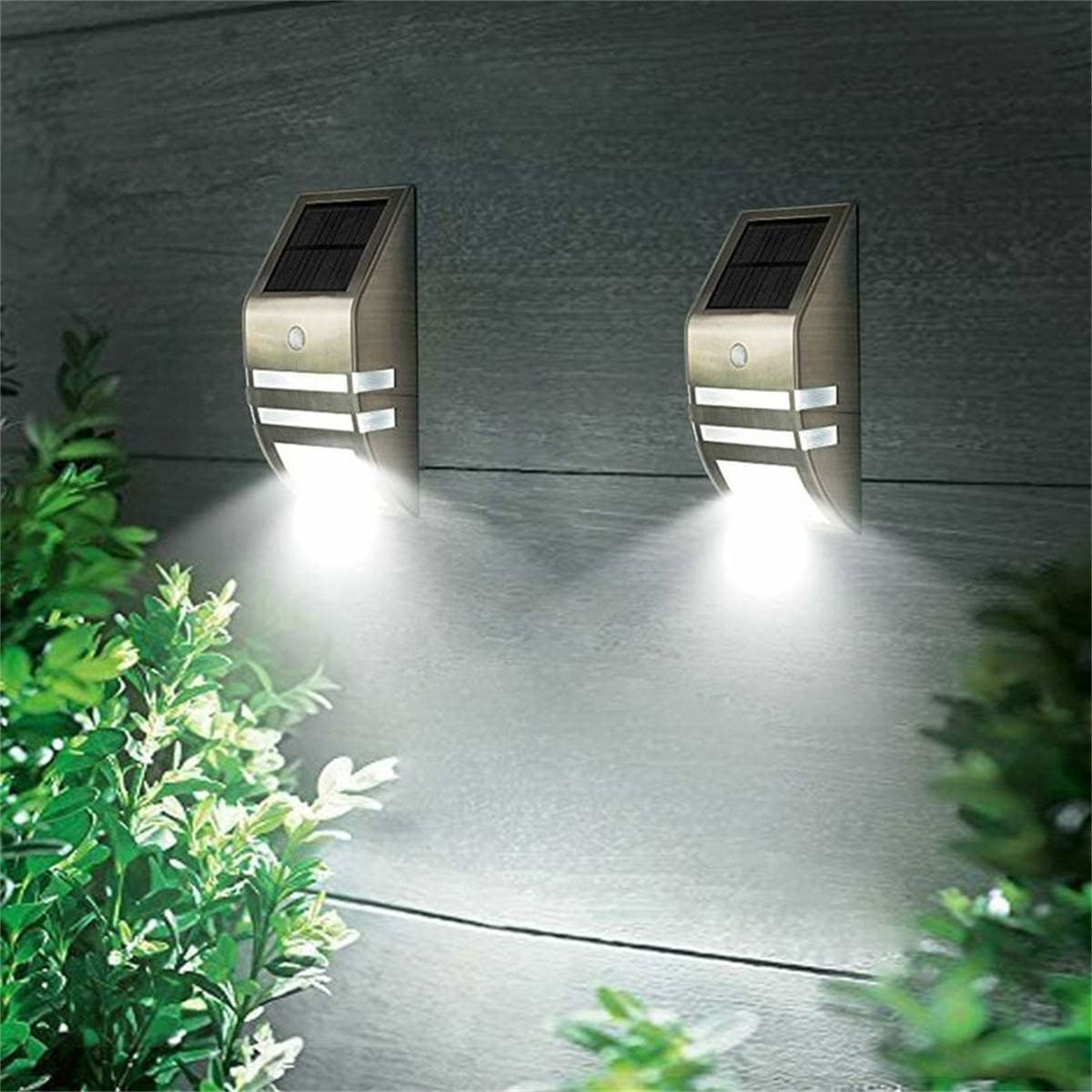 Zwei an der Wand montierte Solarleuchten. Sie befinden sich an einer Wand. Lichter sind an und leuchten. Der Hintergrund ist eine Wand.