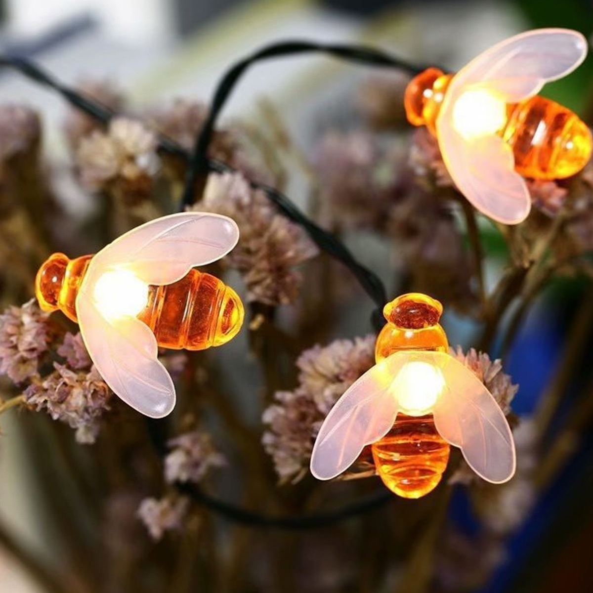 Drei bienenförmige Lichterketten mit orangefarbenen Körpern, weißen Flügeln und schwarzem Draht.