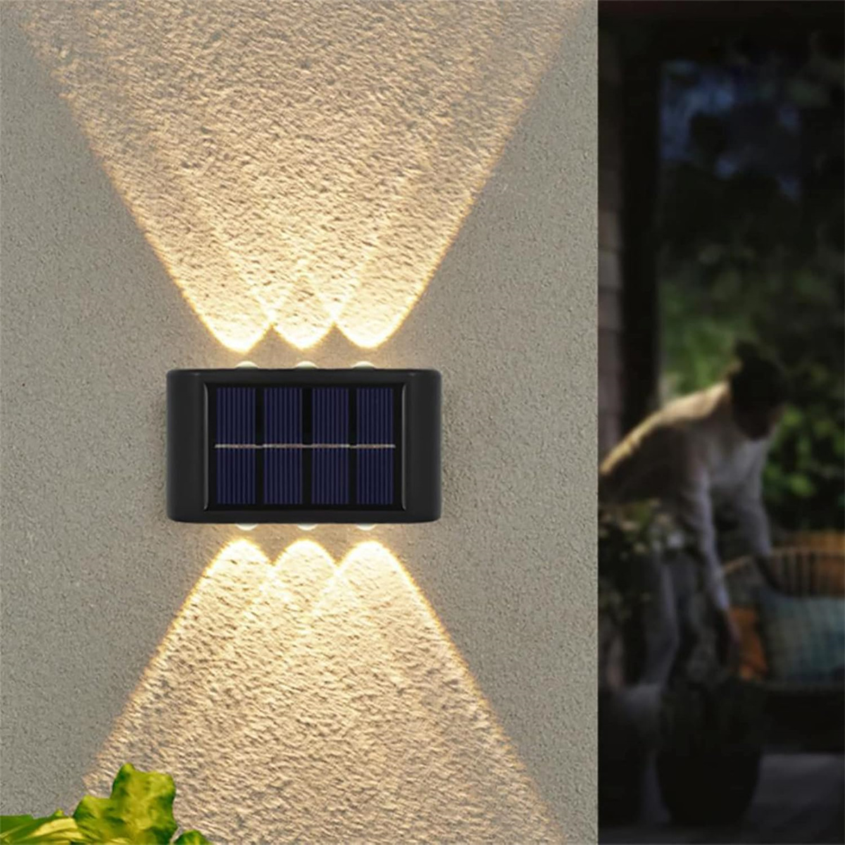 Eine solarbetriebene Wandleuchte mit schwarzem Rahmen, die Licht von ihrem Solarpanel ausstrahlt.