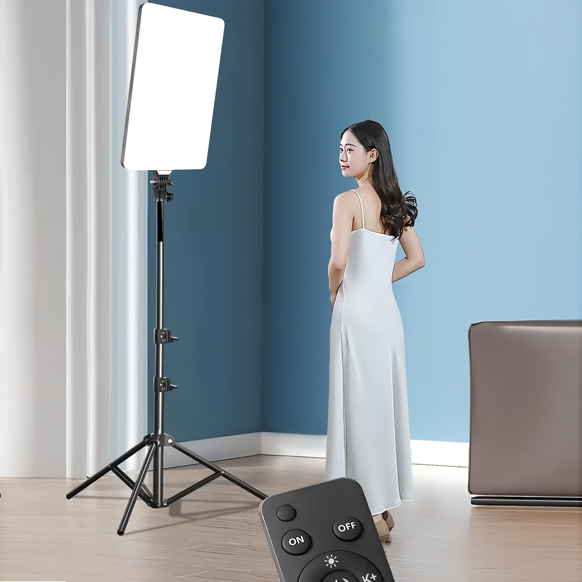 Mujer con vestido blanco junto a luz de estudio, mando en mano. Fondo azul.