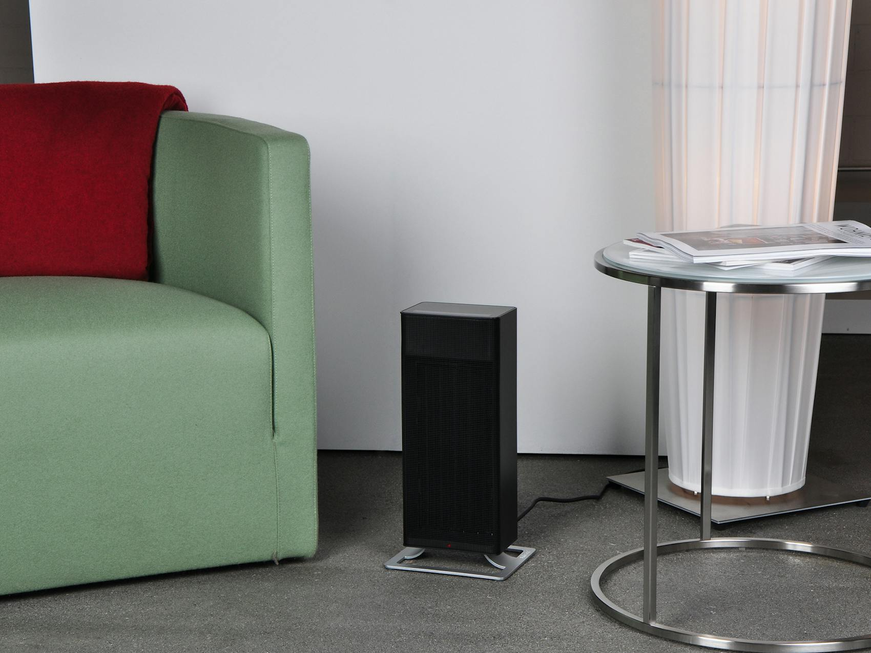 Zwarte kachel op een zilveren standaard. Groene bank en kleine tafel met items op de achtergrond.
