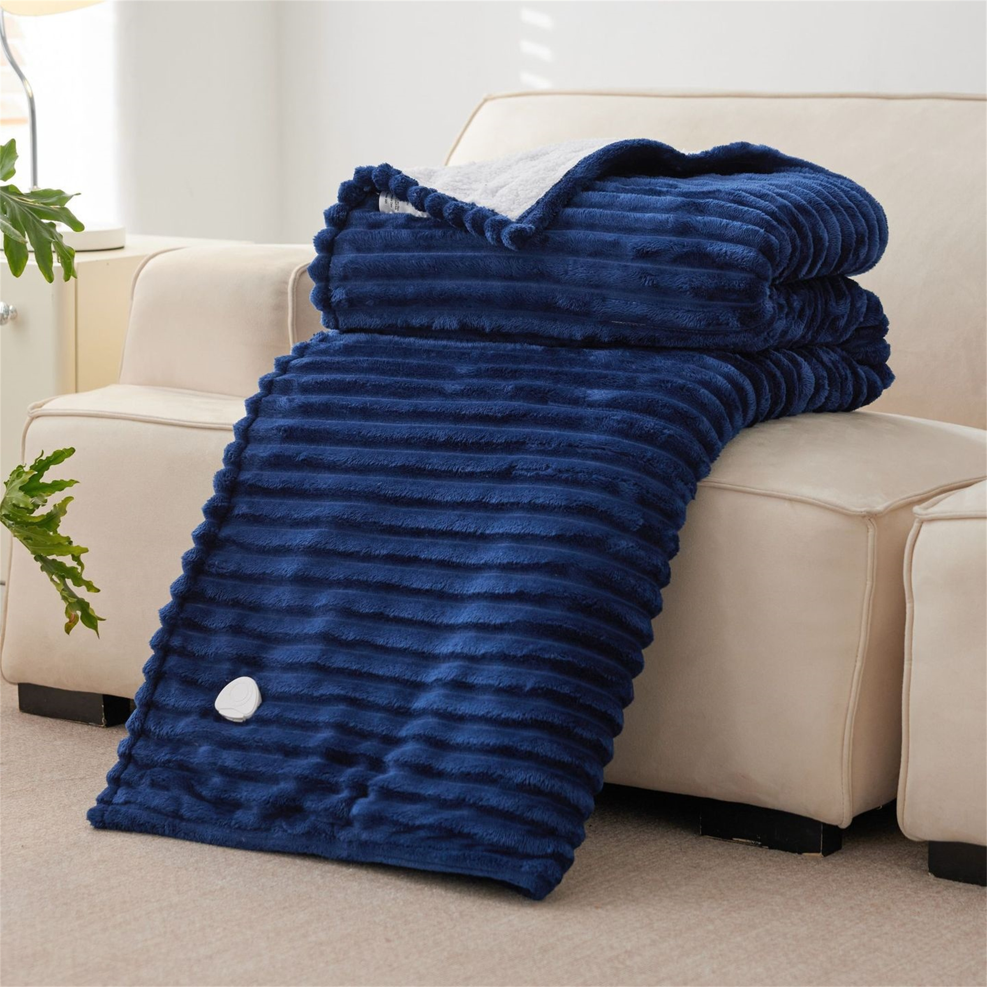 Eine gefaltete blaue Decke auf einem beigen Sofa.