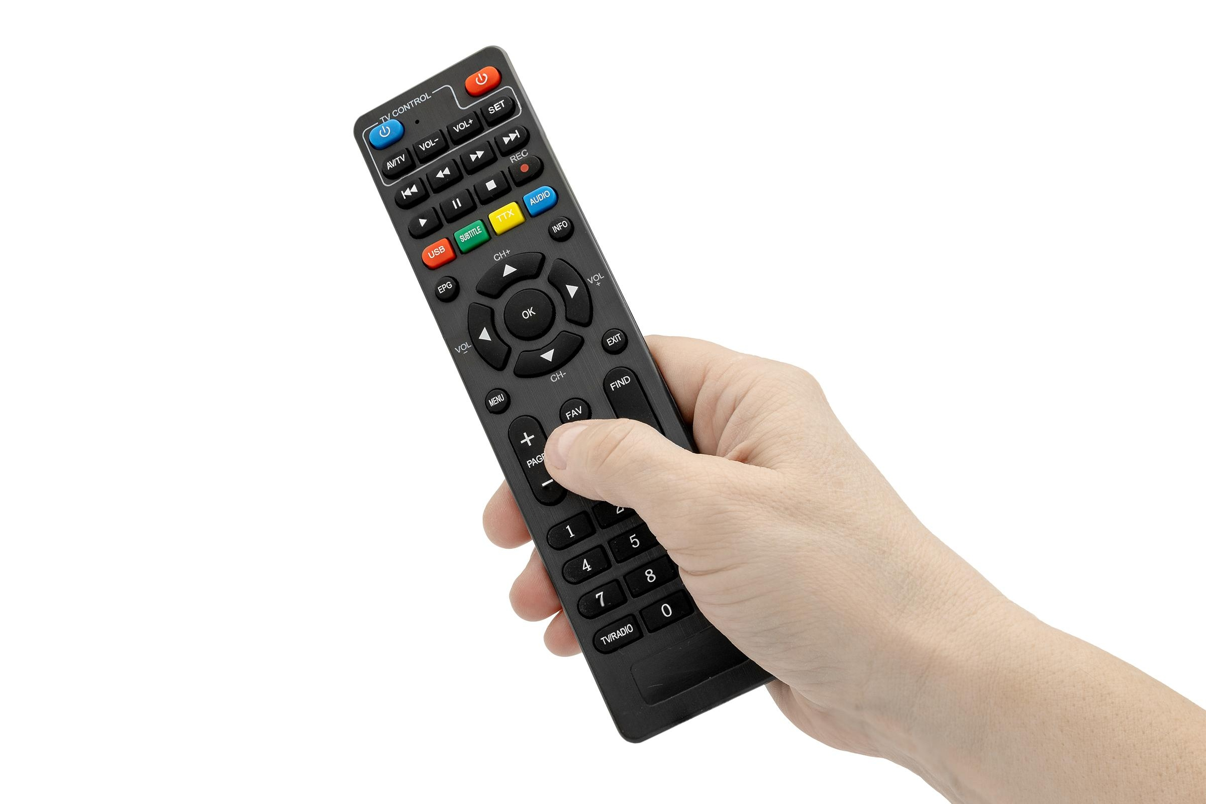 Eine Hand hält eine schwarze TV-Fernbedienung. Tasten für Lautstärke, Kanäle und andere TV-Funktionen.