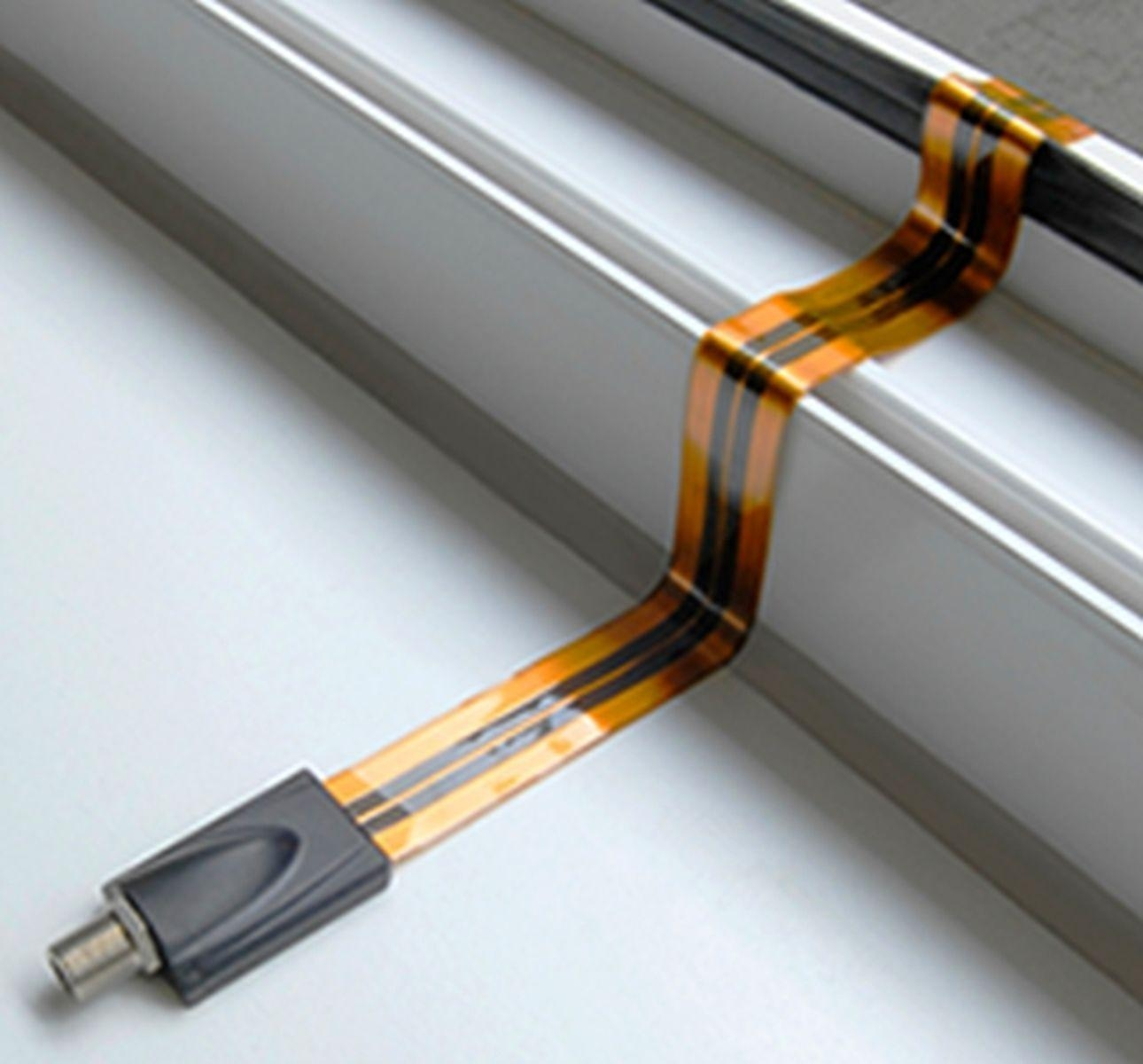 Flexibles Kabel mit Stecker. Das Kabel ist orange und schwarz. Es liegt an einer silbernen Stange.