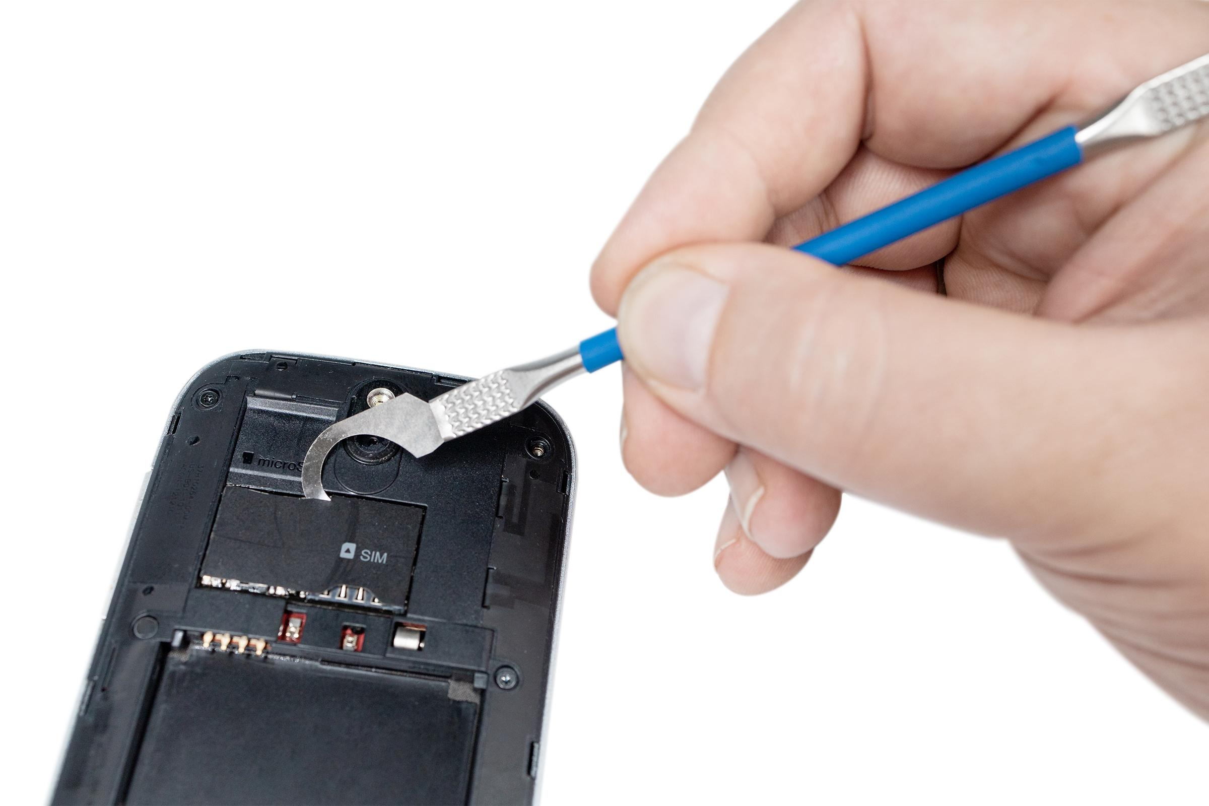 Hand, die mit einem blauen Werkzeug eine SIM-Karte aus einem schwarzen Telefon entfernt.