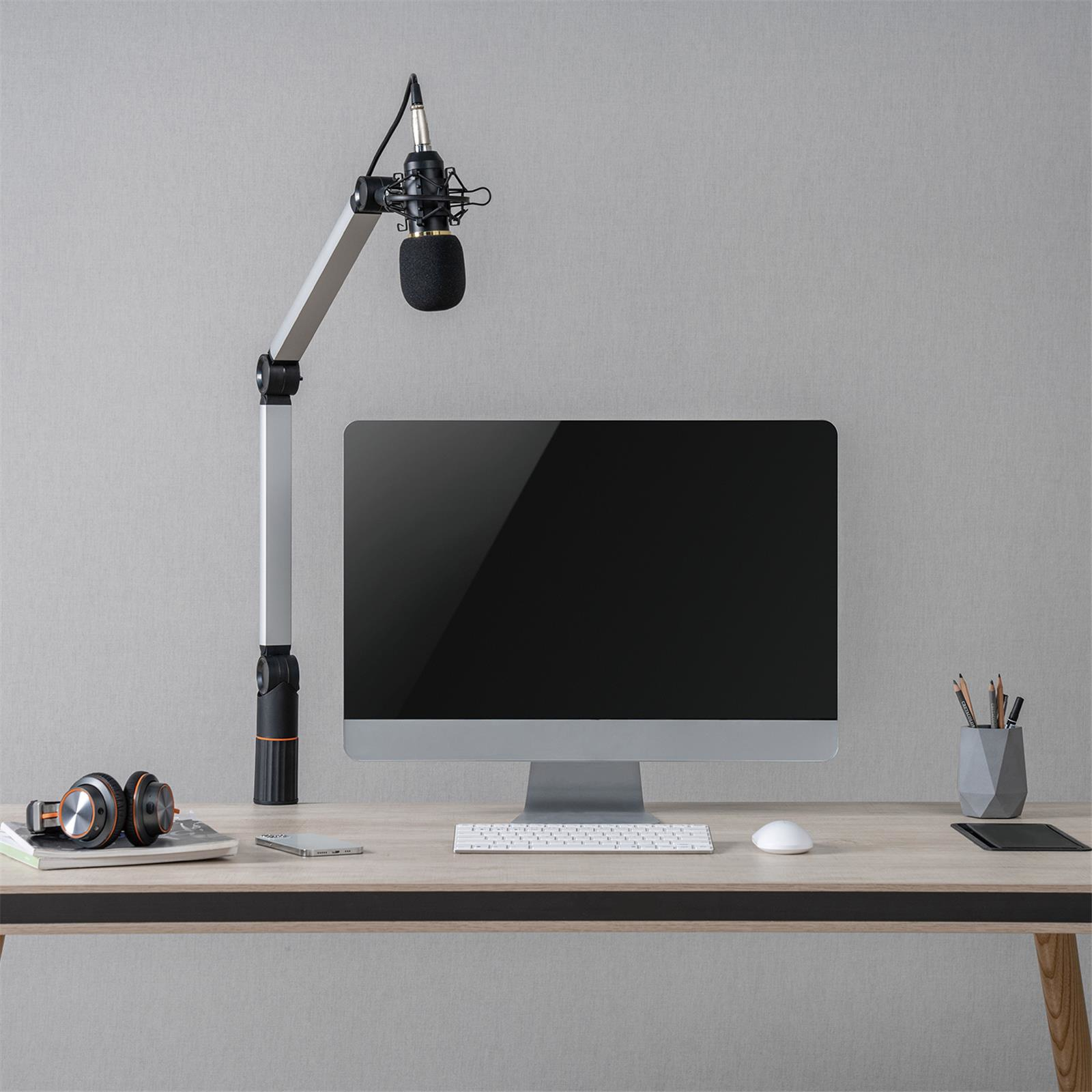 Una configuración de escritorio con un micrófono, un monitor, auriculares, un teclado y un ratón.