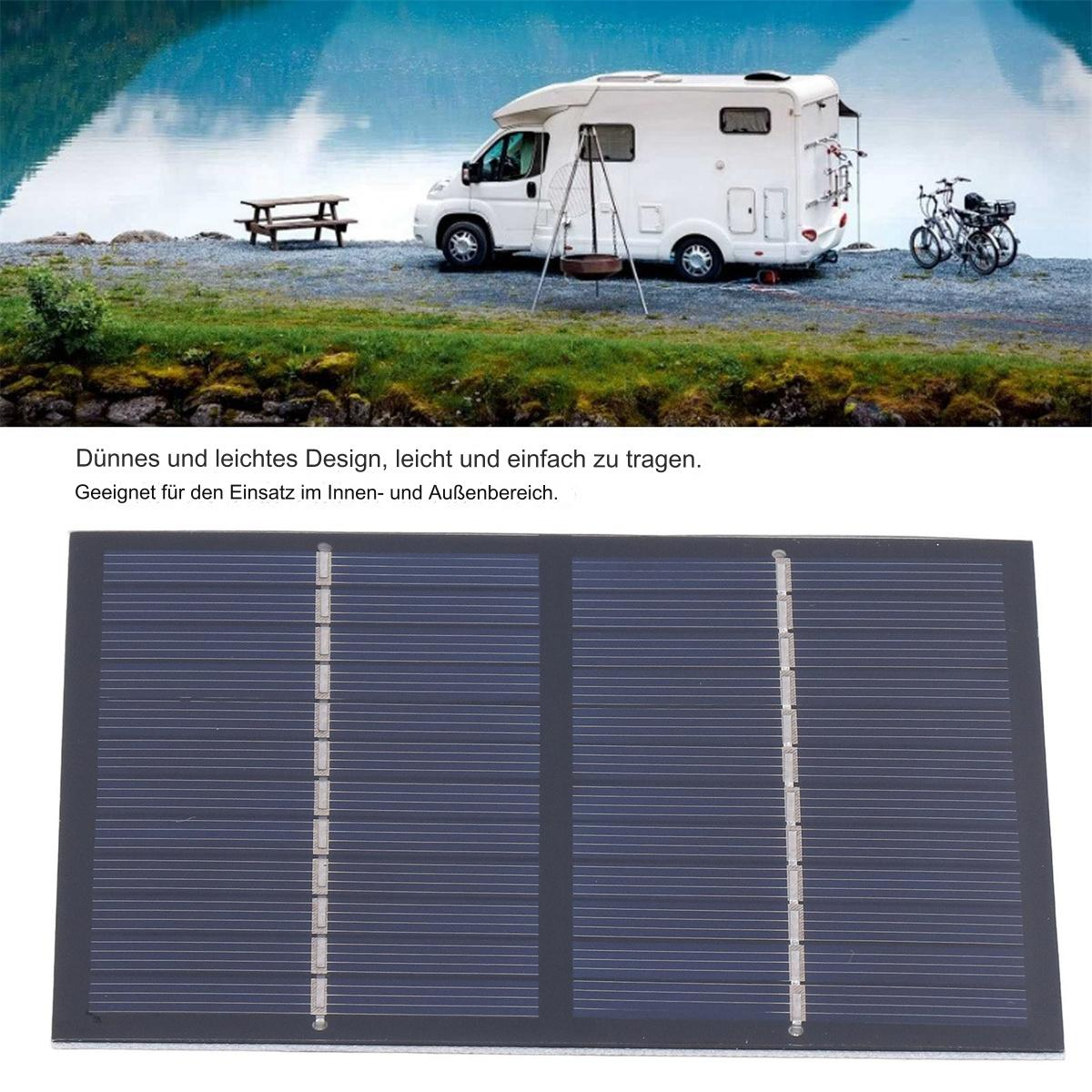 Solarpanel mit weißem Wohnmobil, Picknicktisch und Fahrrädern am Seeufer.