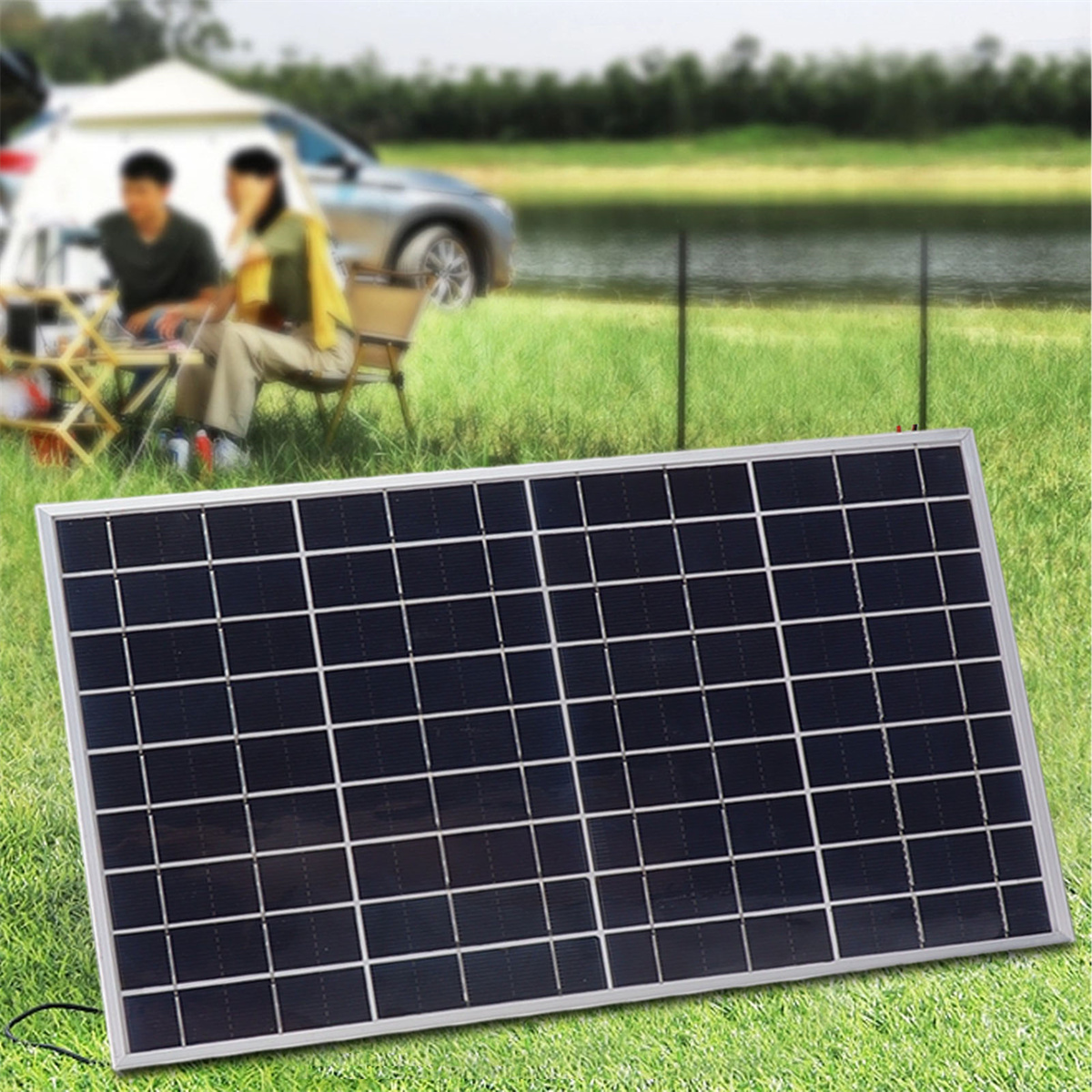 Ein Solarpanel auf Gras. Im Hintergrund befinden sich Menschen in der Nähe eines Autos und eines Zeltes.