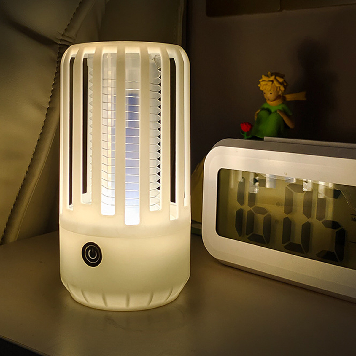 Eine weiße und hellblaue Nachtlampe mit kleiner Figur und Digitaluhr daneben.