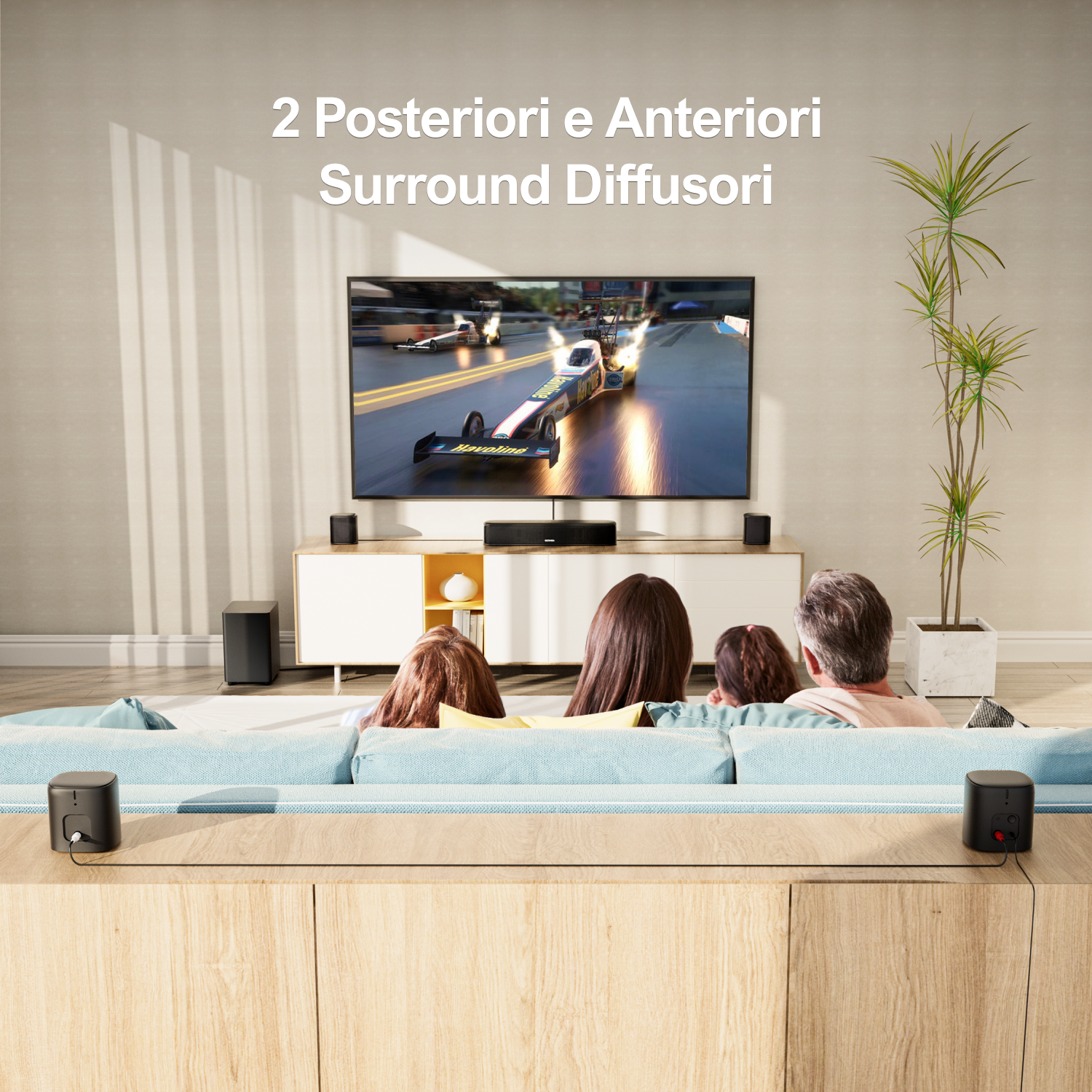 Famiglia guarda gara in TV, circondata da altoparlanti. Pianta a destra. Divano in primo piano.