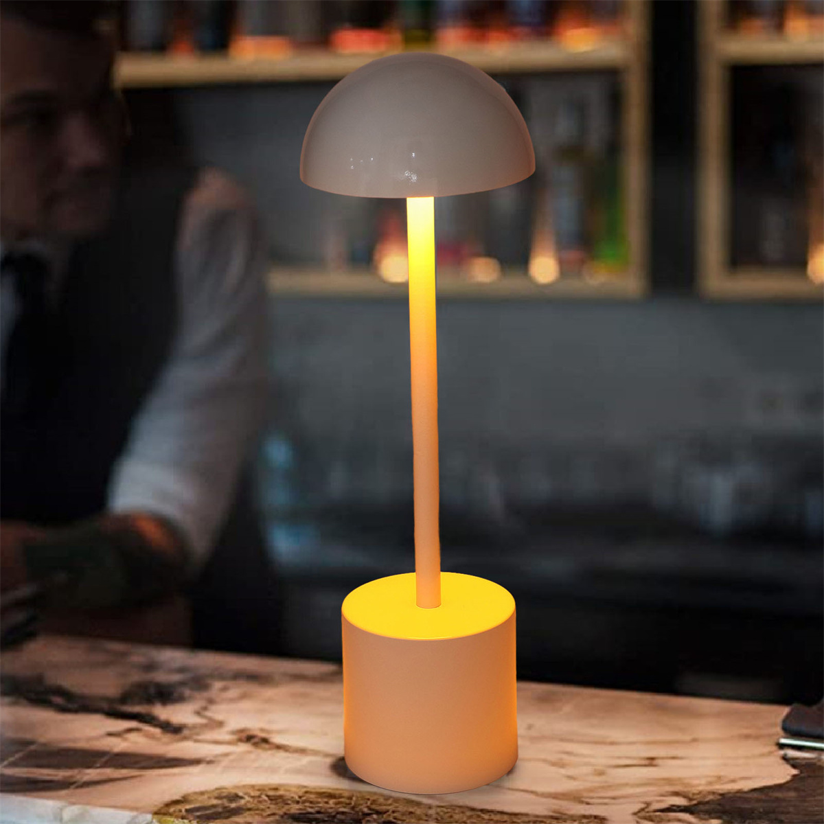 Eine moderne Tischlampe auf einer Arbeitsplatte. Die Lampe hat eine abgerundete Oberseite und einen zylindrischen Fuß.