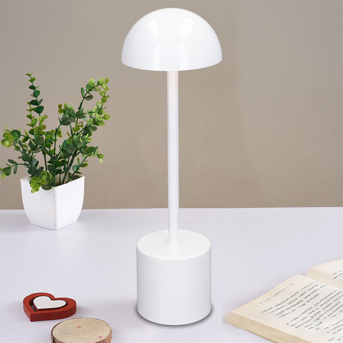 Eine weiße Lampe, eine Pflanze, ein Buch und eine herzförmige Dekoration.