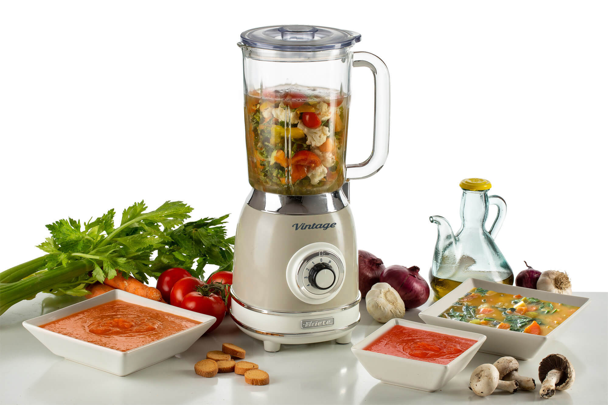İçinde sebzeler bulunan eski model bir blender, çorba kaseleri ve diğer malzemeler.