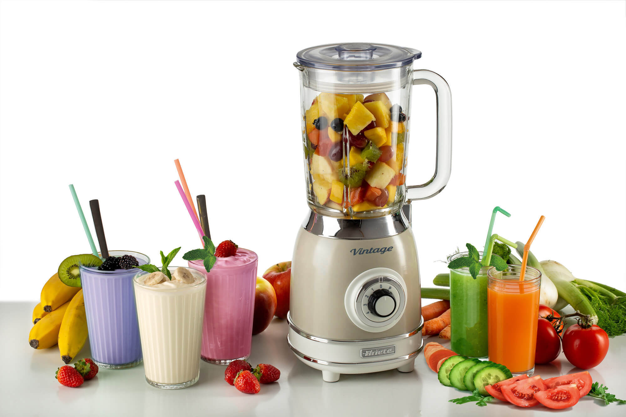 Meyve ve smoothie'lerle bir blender. Etrafına birkaç bardak smoothie ve taze meyve yerleştirilmiş.