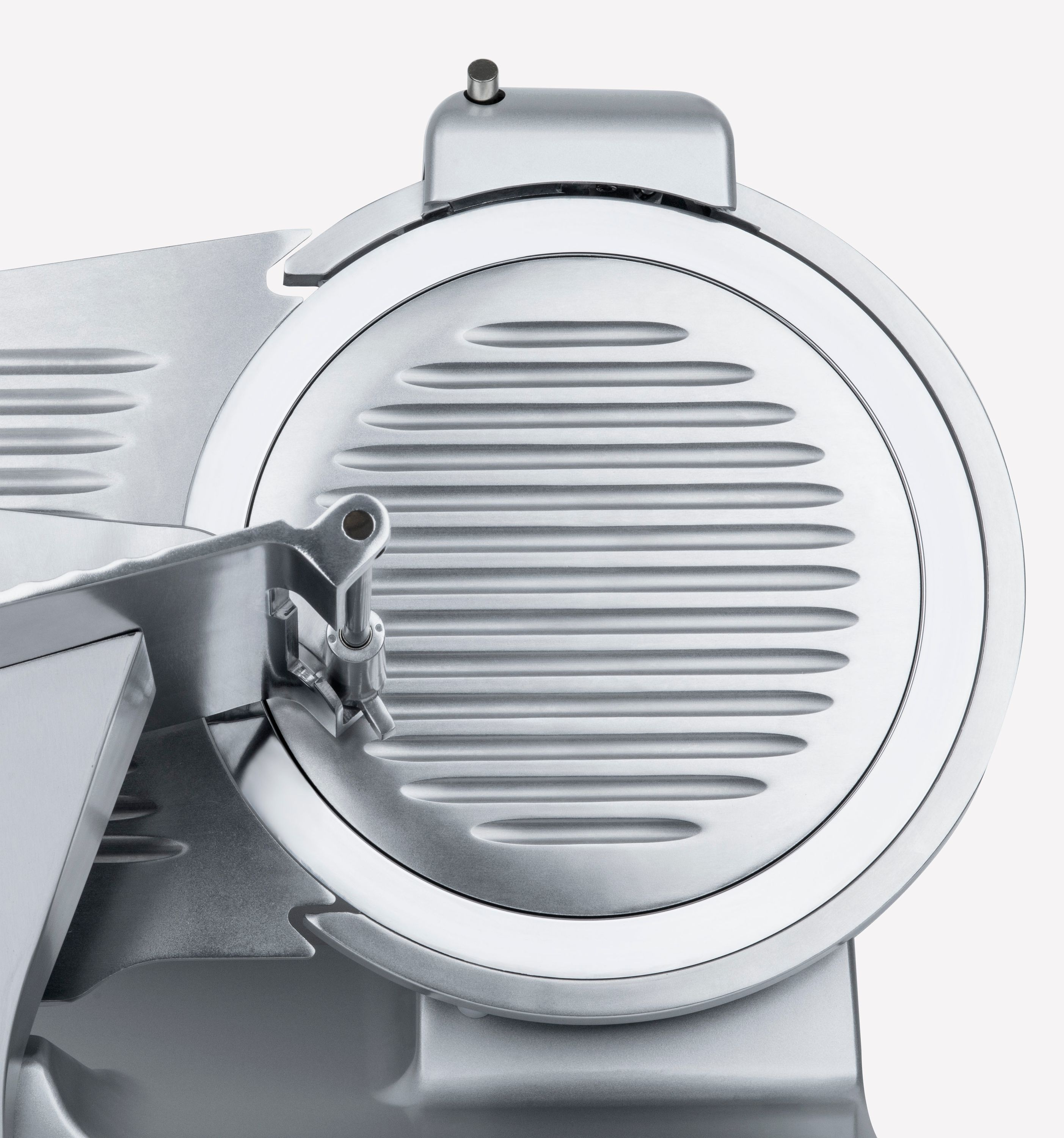 Srebrna krajalnica do mięsa. Ostrze jest okrągłe z poziomymi rowkami. Na białym tle.