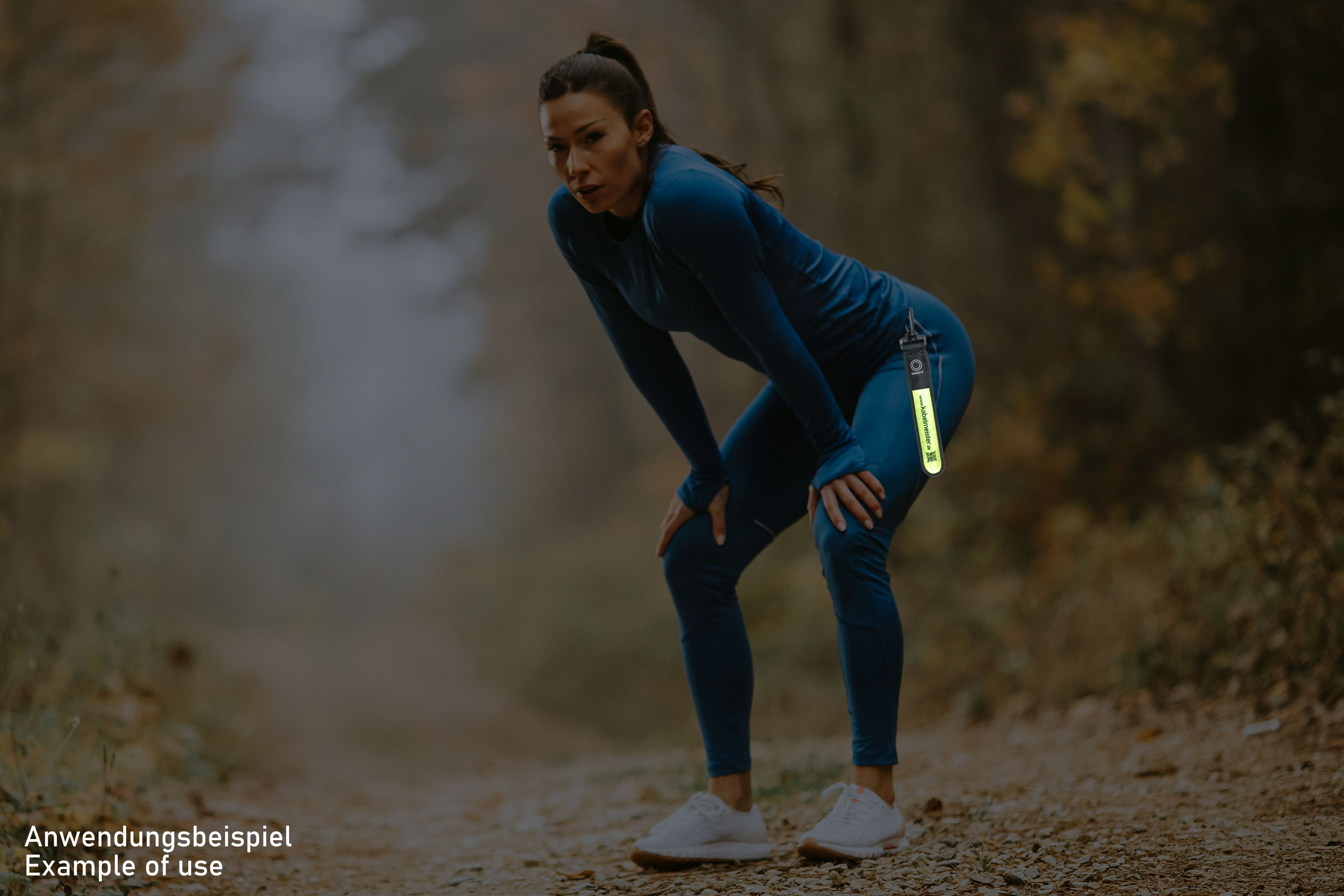 Eine Frau in Sportkleidung beugt sich. Ein reflektierendes Band ist am Ärmel ihrer Jacke befestigt.