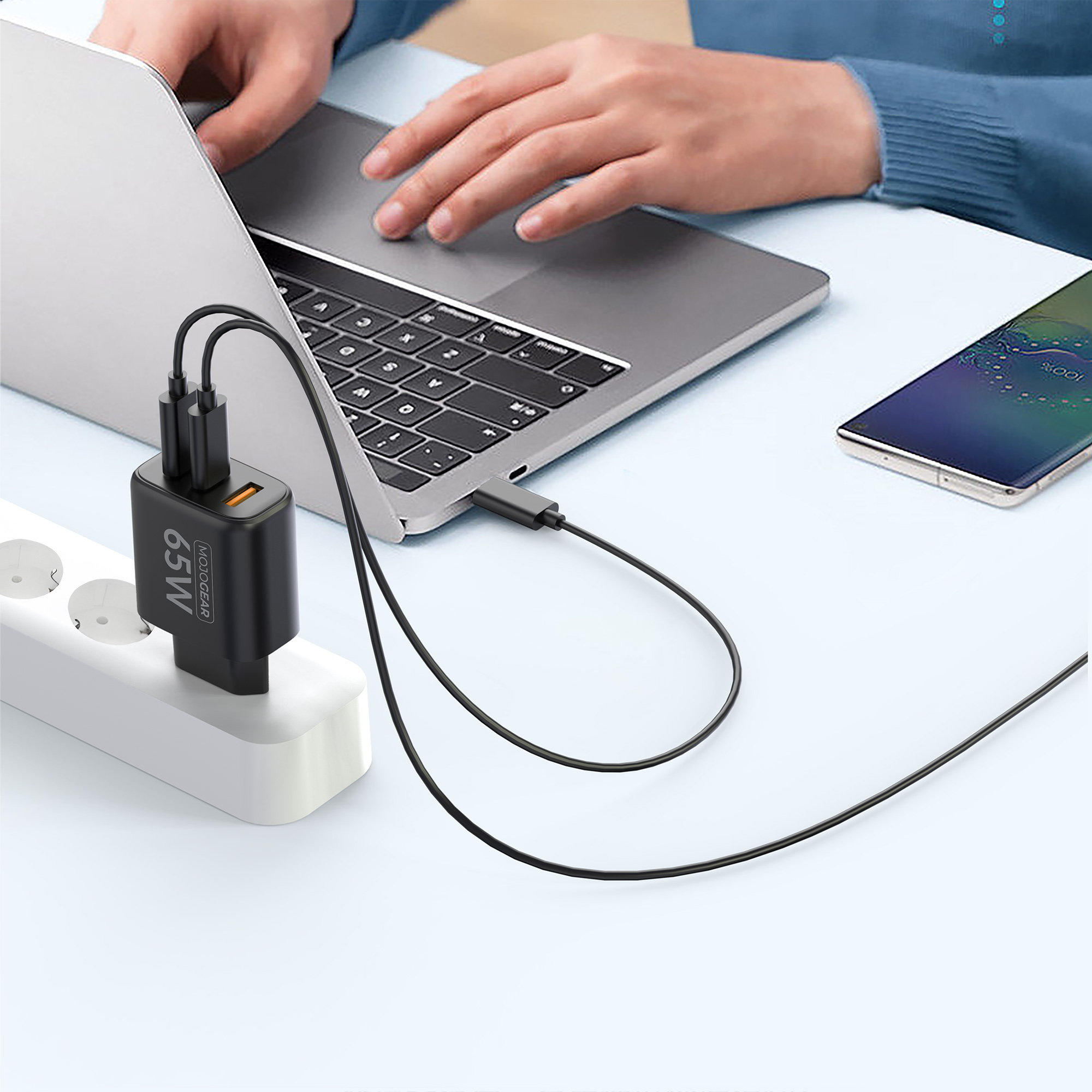 Ein Laptop, der an einen Netzadapter angeschlossen ist und ein Telefon lädt.
