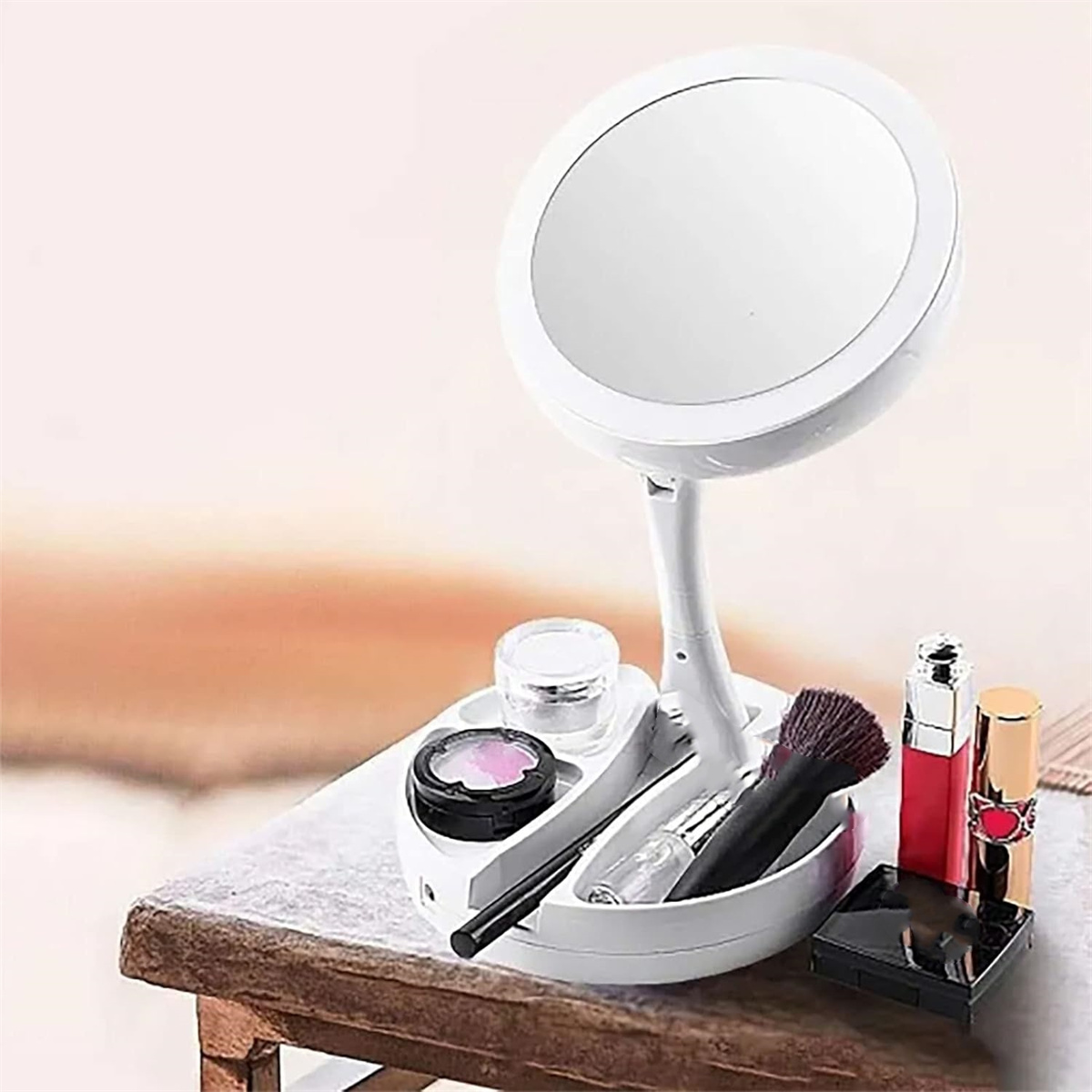 Weißer Schminkspiegel mit Kosmetika auf einem Holztisch, einschließlich Pinsel und Lippenstifte.