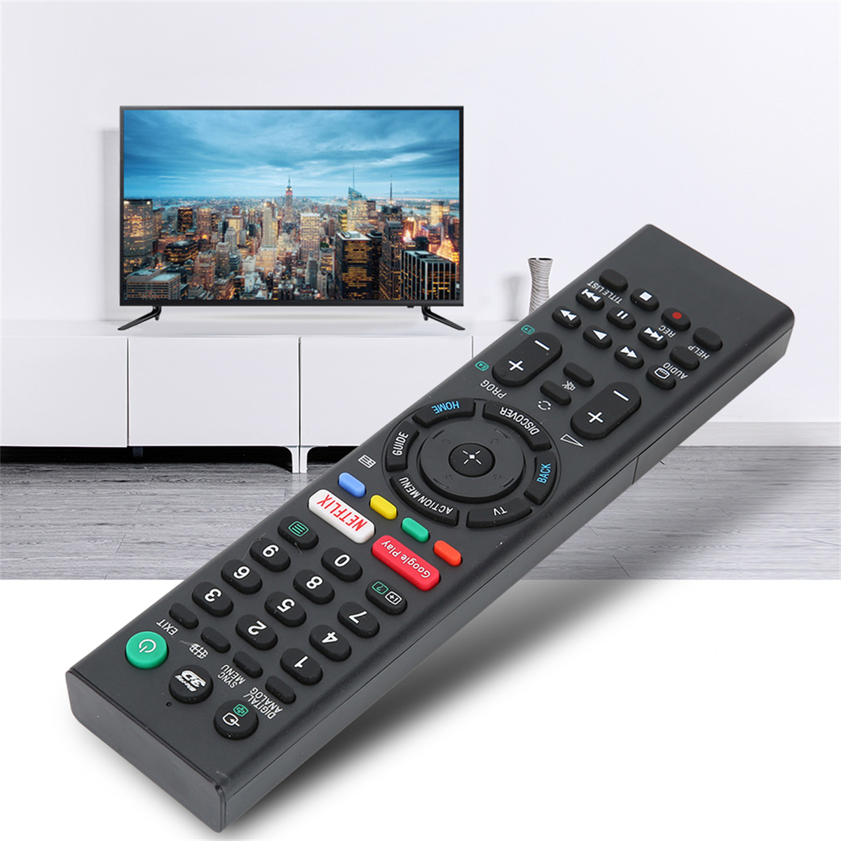 Schwarze Fernbedienung mit vielen Knöpfen, zum Betrachter geneigt, mit einem Fernseher im Hintergrund.