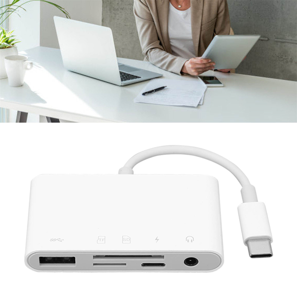 Ein weißer Multiport-Adapter mit Kabel, Laptop und Tablet im Hintergrund.