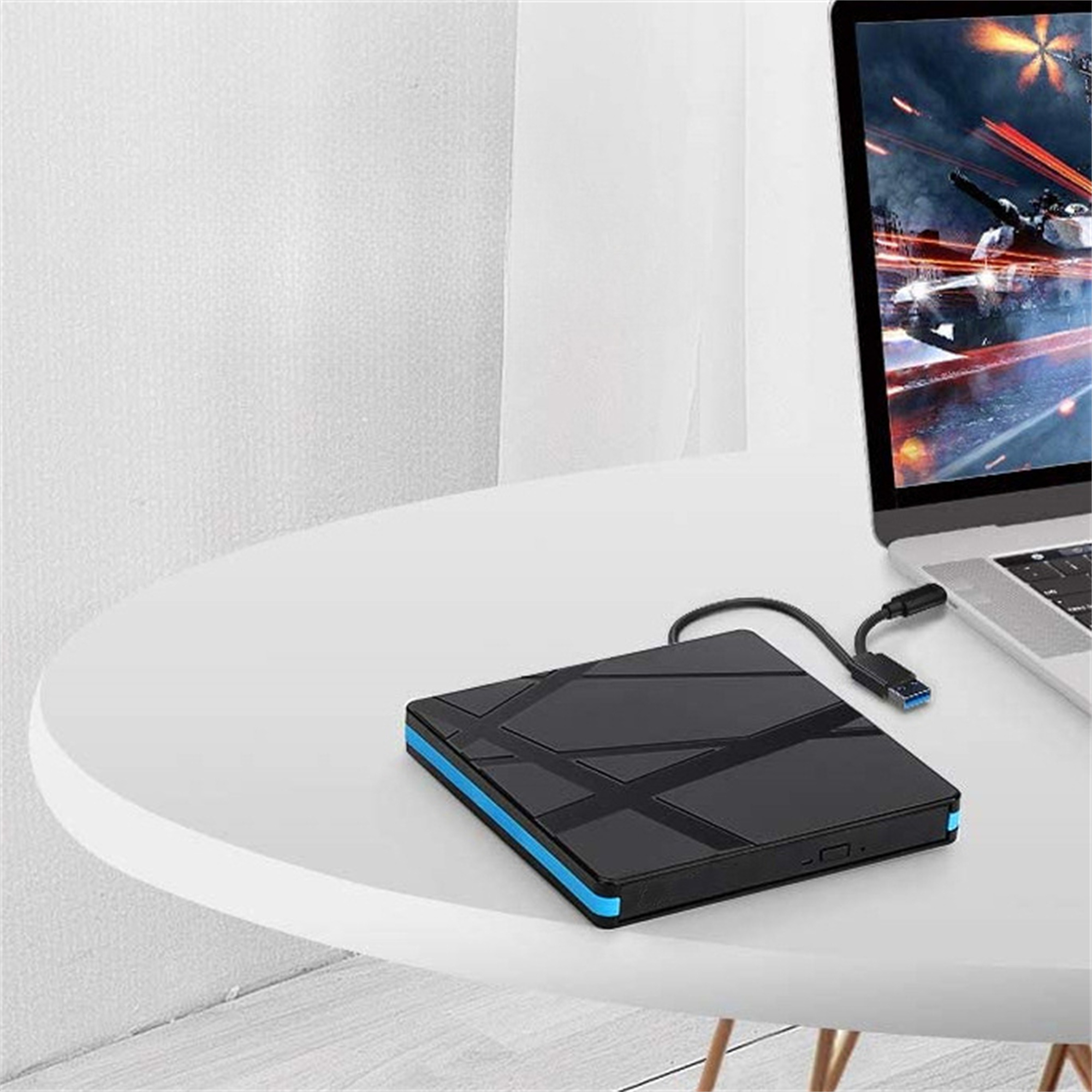 Eine schwarze externe Festplatte, die an einem Laptop auf einem weißen Tisch angeschlossen ist. Blaue Zierleiste sichtbar.