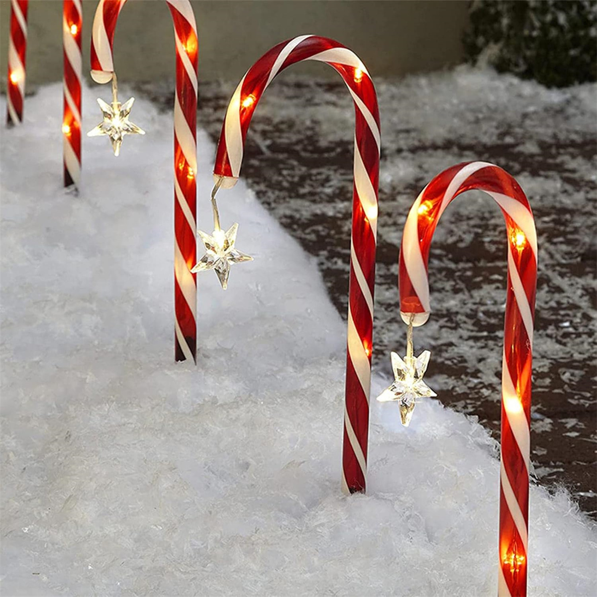 Zuckerstangenlichter in einem schneebedeckten Bereich, mit sternförmigen Ornamenten.
