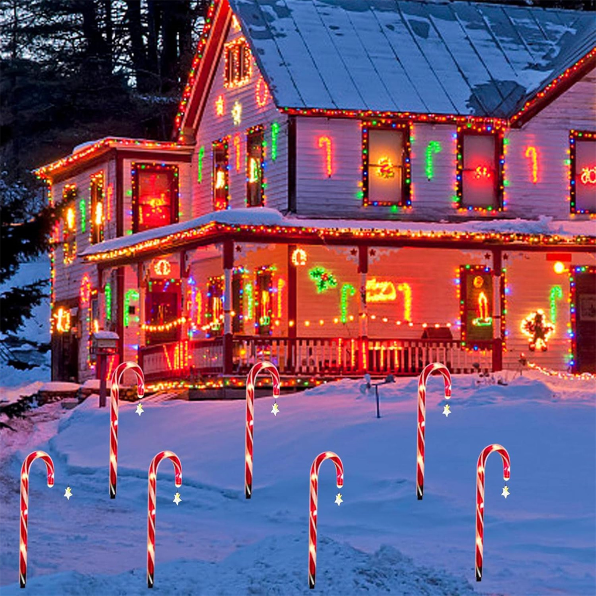 Ein Haus mit Weihnachtsbeleuchtung und Zuckerstangen-Dekorationen in einem verschneiten Garten.
