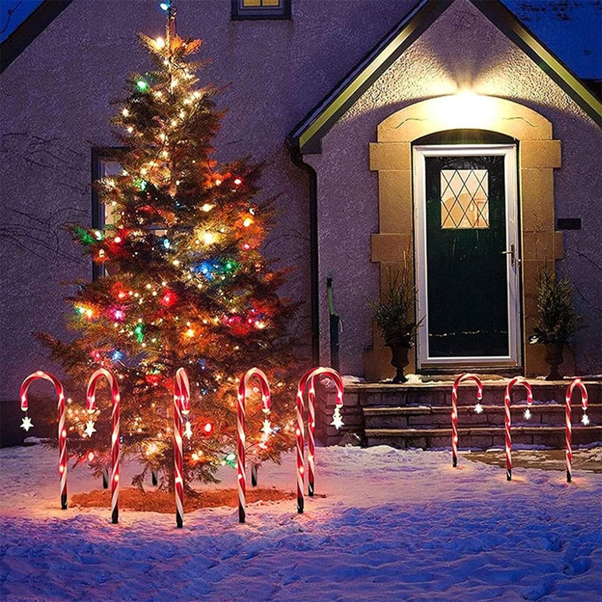 Weihnachtsszene in der Abenddämmerung. Beleuchteter Weihnachtsbaum, Zuckerstangenlichter, Haus mit Lichtern.