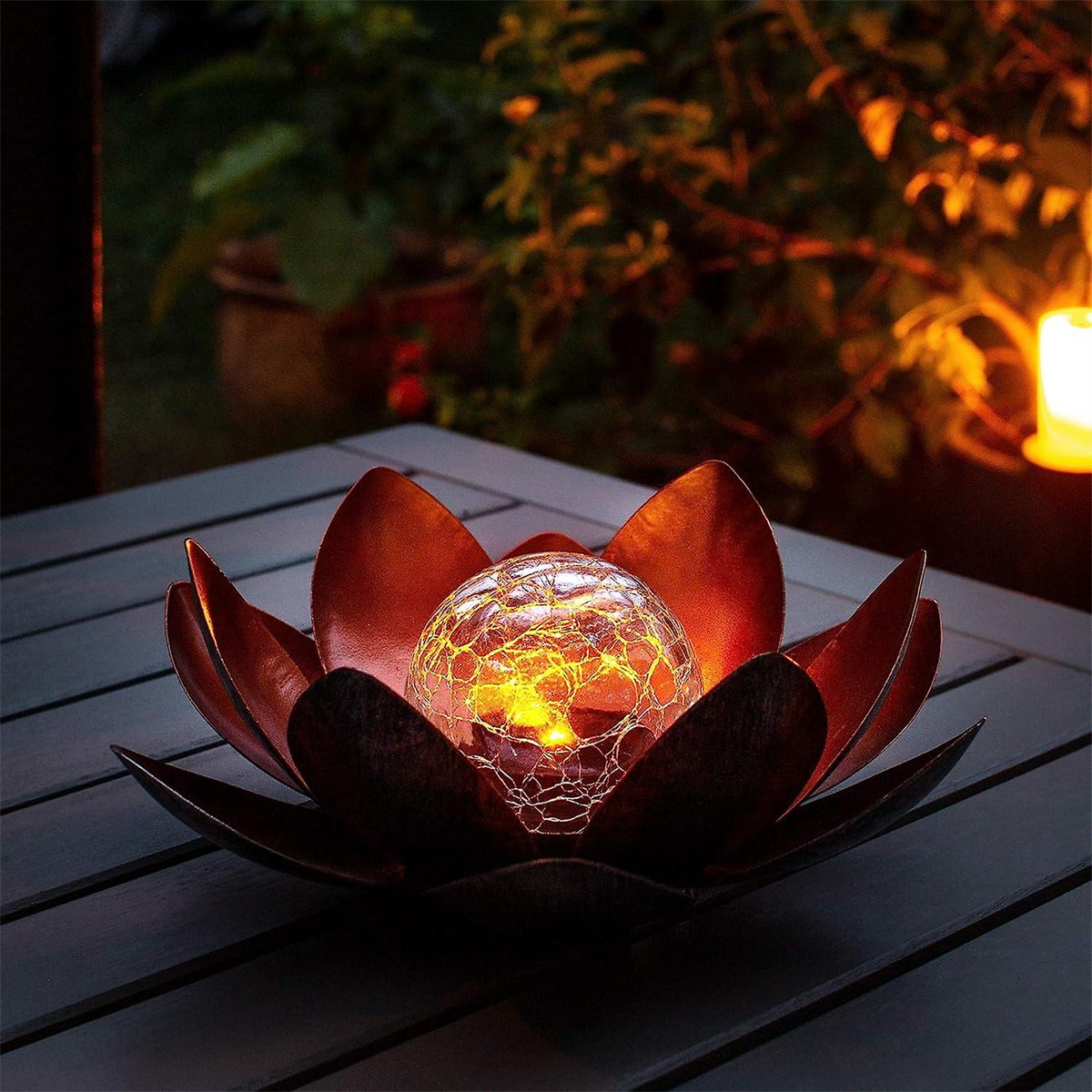 Dekorative Solar-Lotusblumenleuchte mit leuchtender Kugel auf einem Tisch.