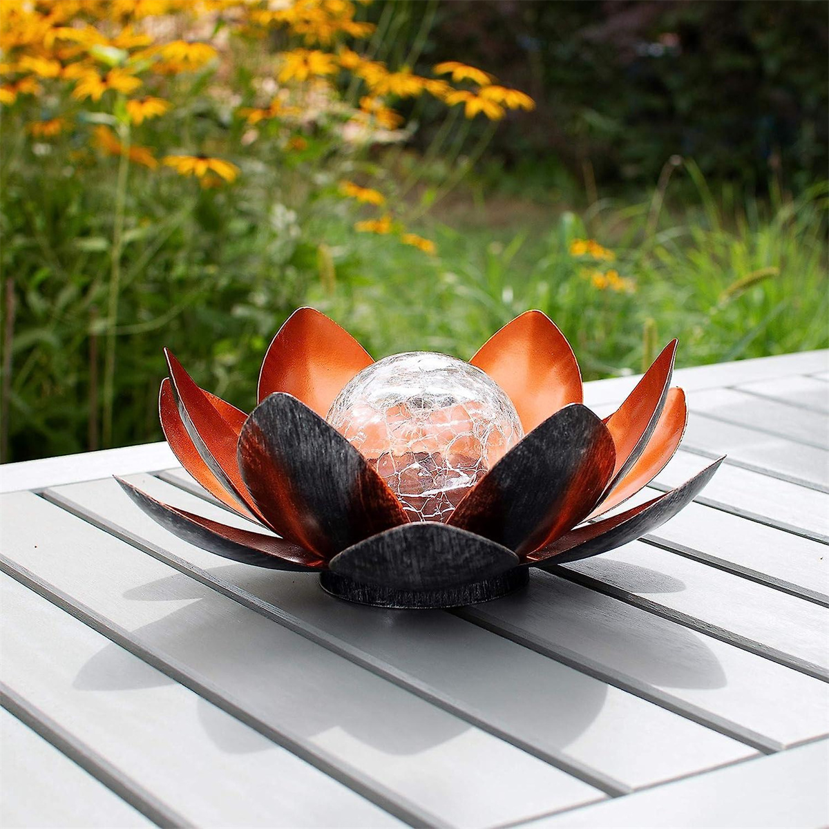 Kupferfarbene Lotusblumen-Dekoration mit einer Glaskugel auf einem grauen Tisch.