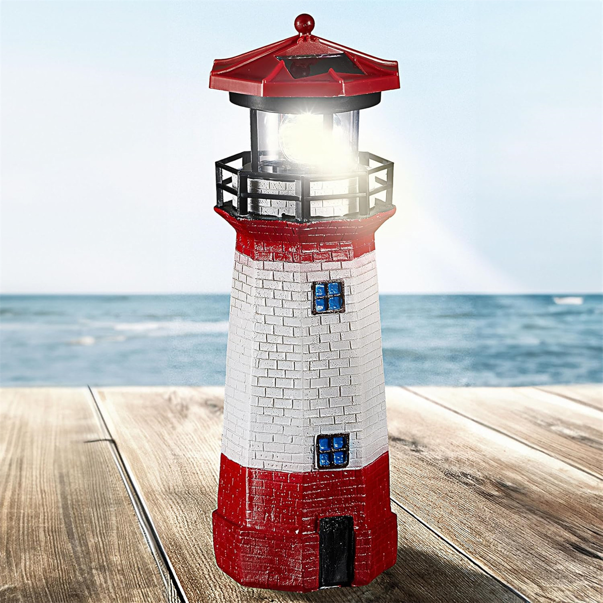 Eine dekorative Leuchtturmlampe auf einer Holzoberfläche. Der Hintergrund ist Wasser und Himmel.