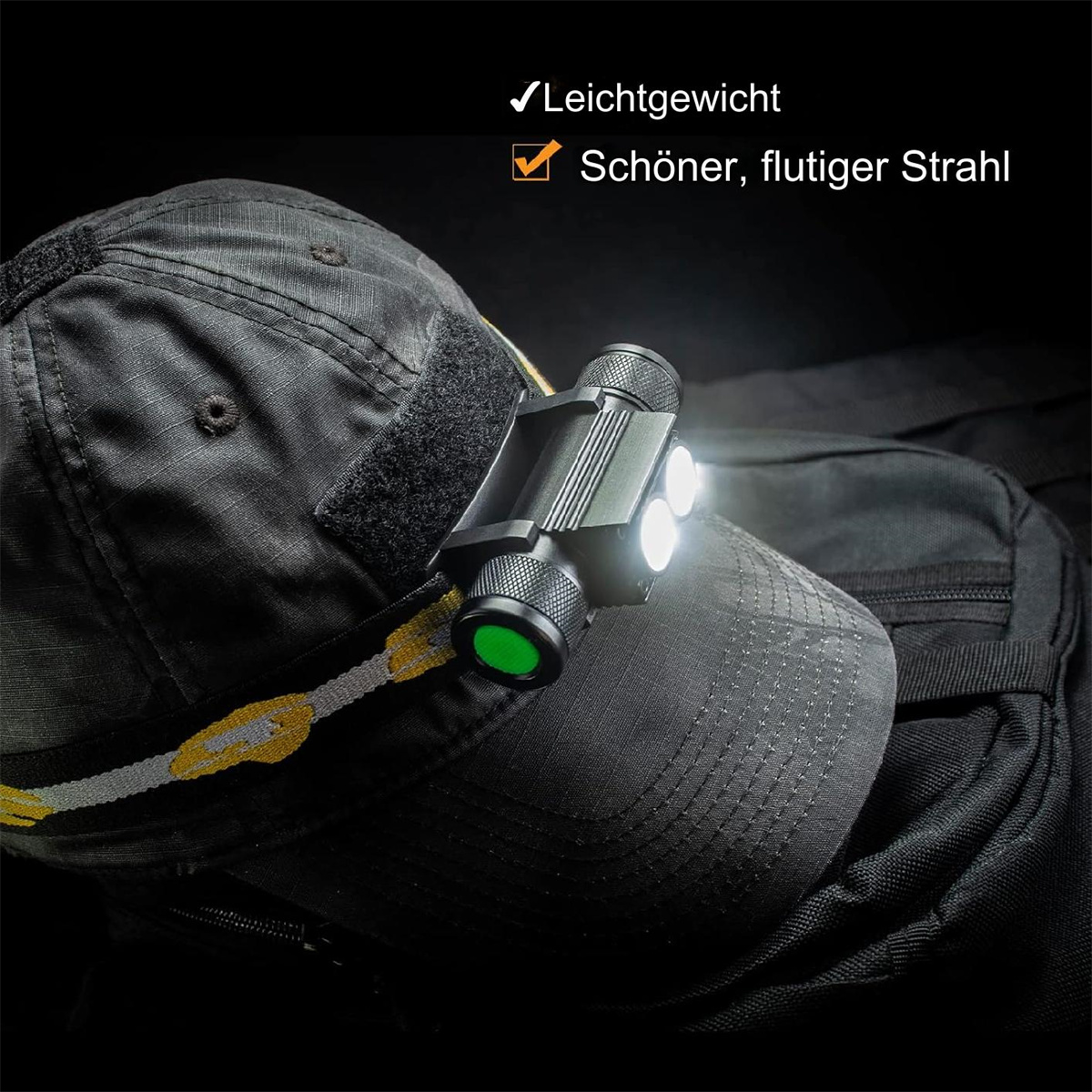 Eine schwarze Stirnlampe an einer schwarzen Baseballkappe. Die Lampe hat drei weiße und eine grüne Leuchte.