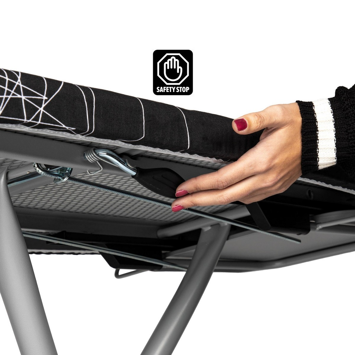 Mano de mujer manipulando una tabla de planchar. Visible el icono 'SAFETY STOP'.