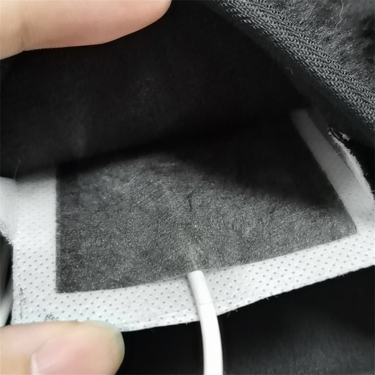 Nahaufnahme eines grauen Heizkissens mit weißem Kabel und grauem Innenraum.