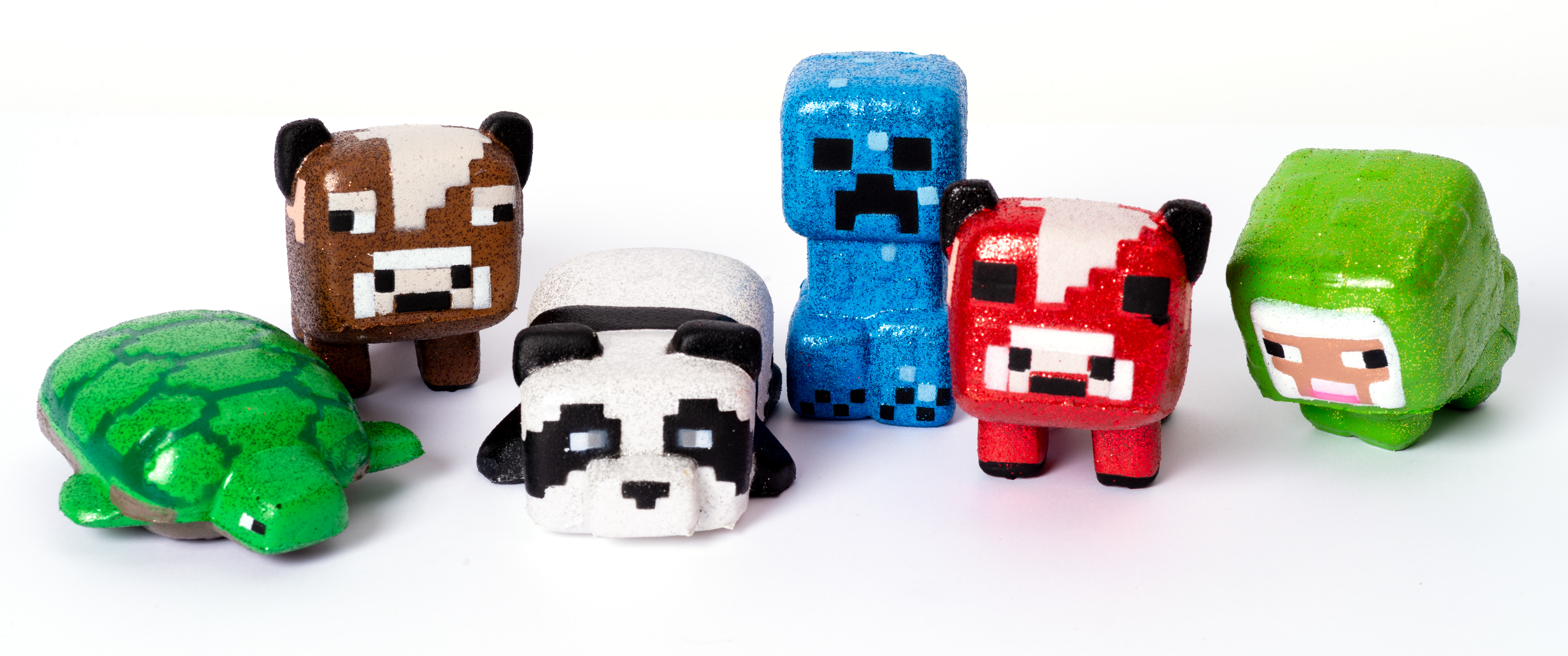 Sechs Minecraft-Figuren auf einer weißen Oberfläche. Zu den Figuren gehören eine Schildkröte, ein Panda, ein Creeper und ein Schaf.