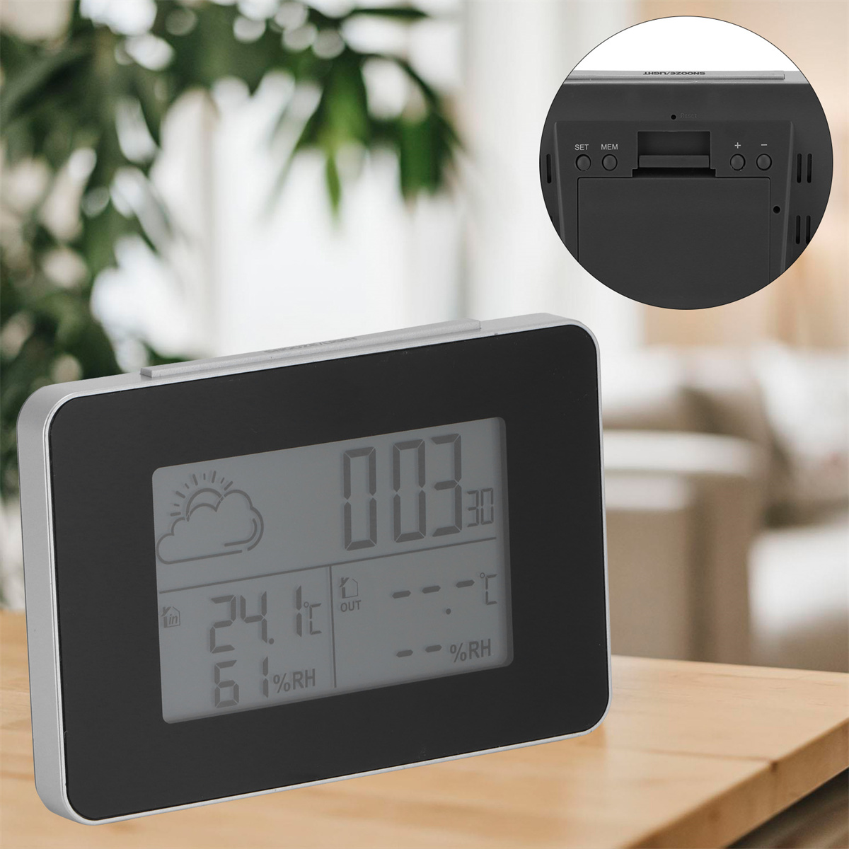 Schwarze und silberne Digitaluhr, die Zeit- und Wetterinformationen anzeigt. Der Hintergrund ist ein verschwommenes Interieur.
