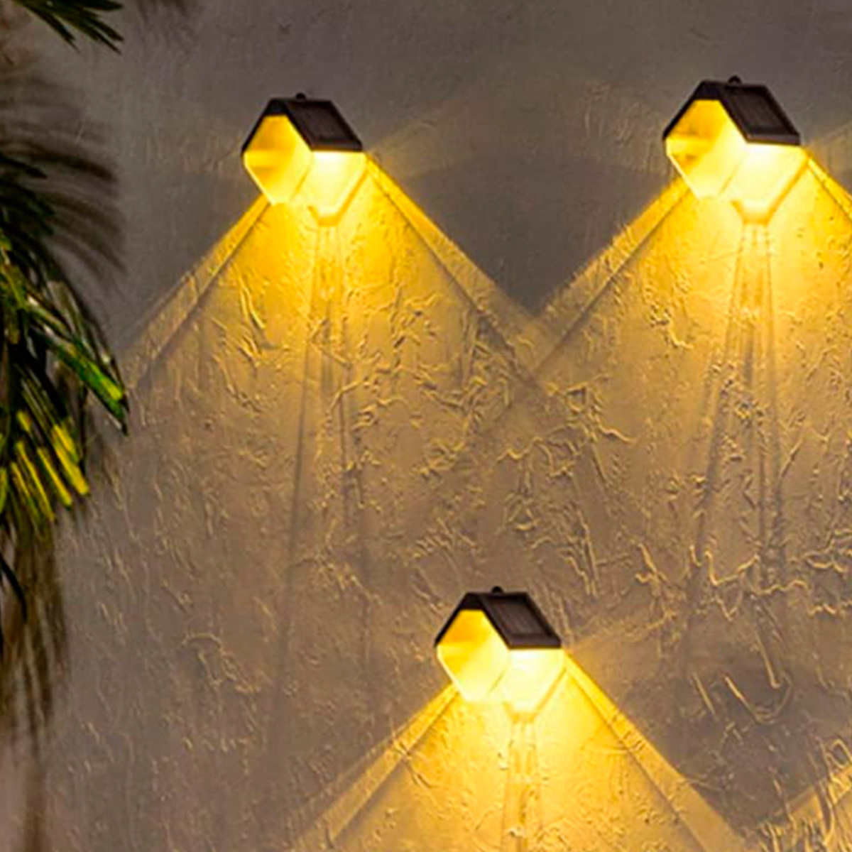 Drei Solarlampen an der Wand, goldenes Licht, Schatten, Außenbeleuchtung.