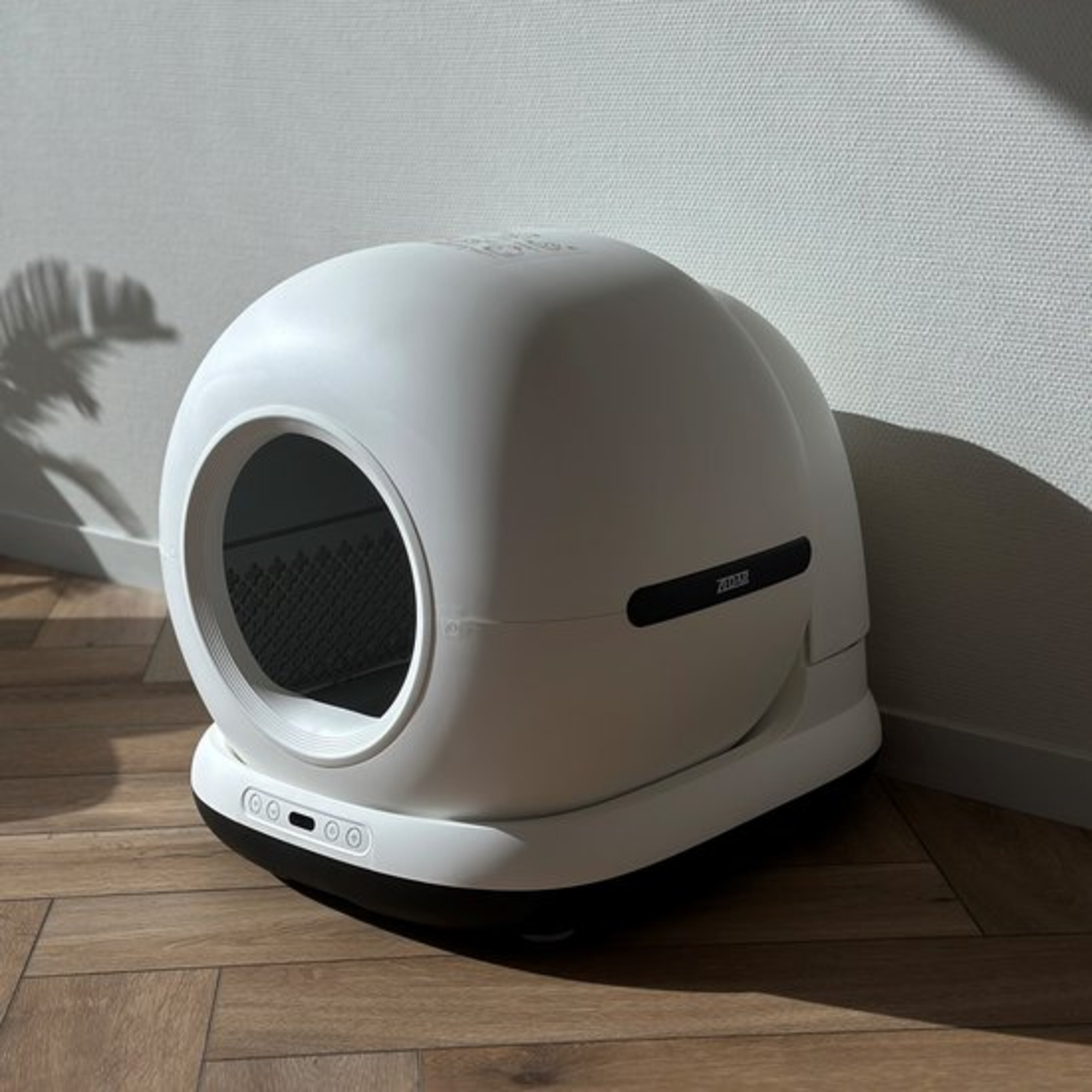 White cat litter box on a wooden floor.