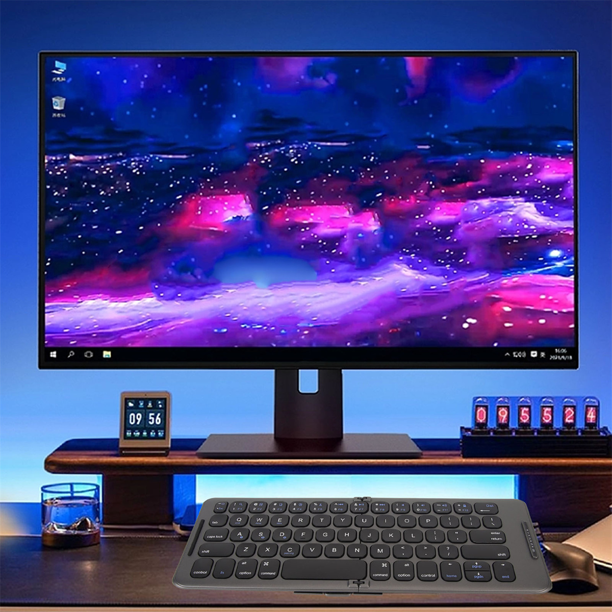 Ein Monitor zeigt einen bunten Bildschirm. Eine Tastatur und eine Uhr befinden sich unten.