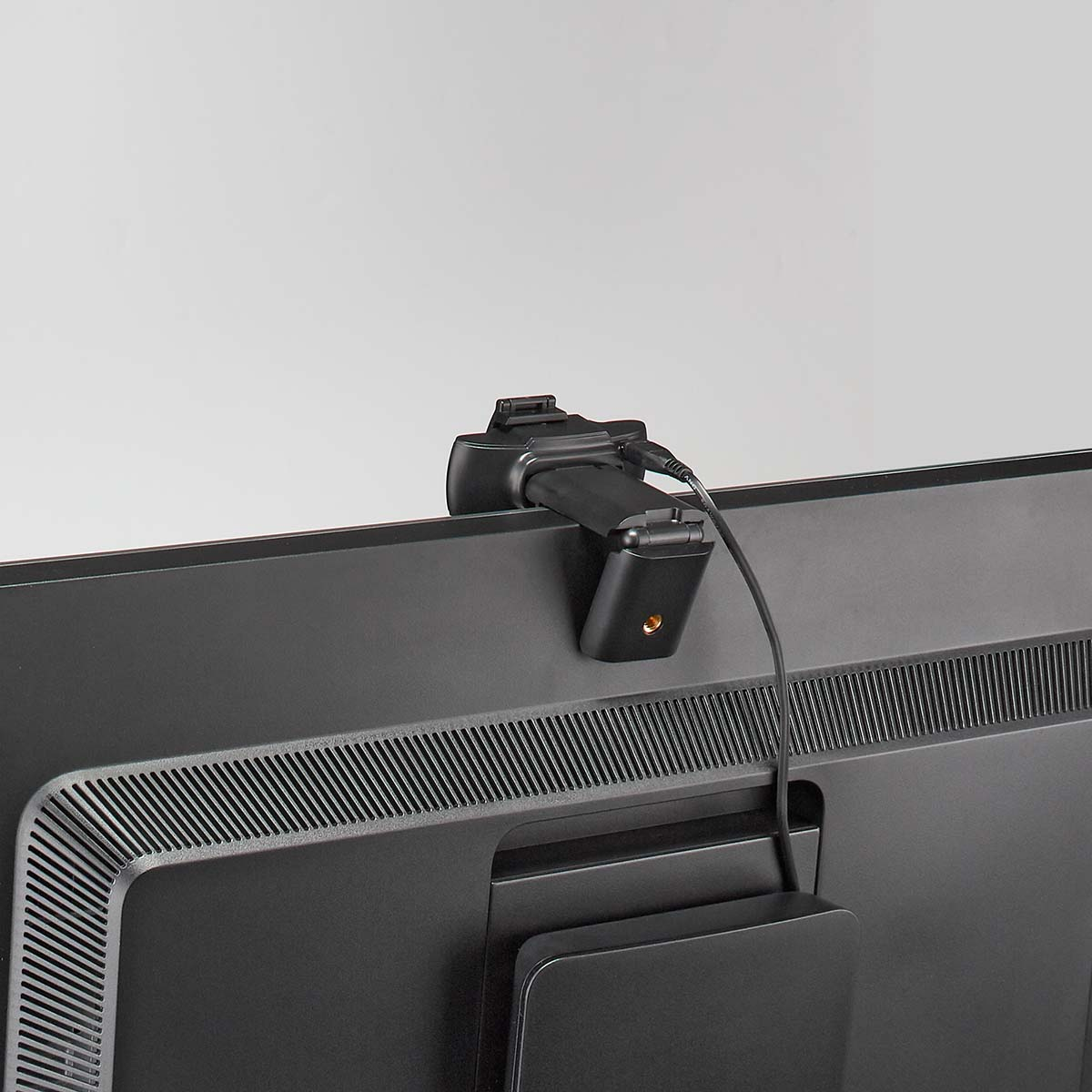 Czarne urządzenie przymocowane do tyłu telewizora. Kabel biegnie z urządzenia.