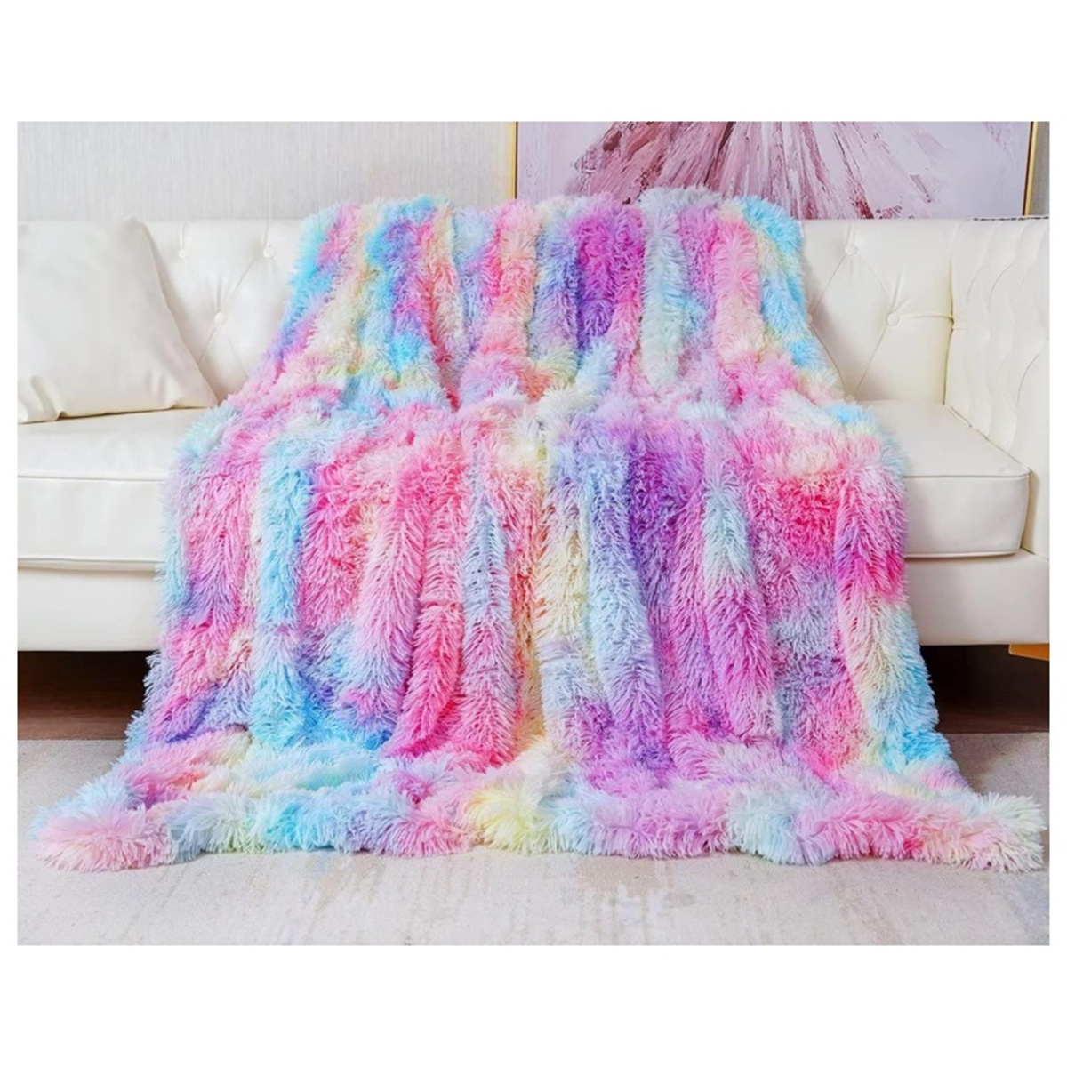 Flauschige, mehrfarbige Decke auf einem weißen Sofa. Farben umfassen Rosa, Blau, Gelb und Lila.