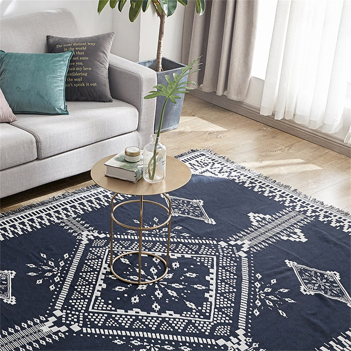 Ein blauer Teppich mit weißem geometrischen Muster liegt auf dem Boden. Ein kleiner Tisch mit Blumen steht oben.