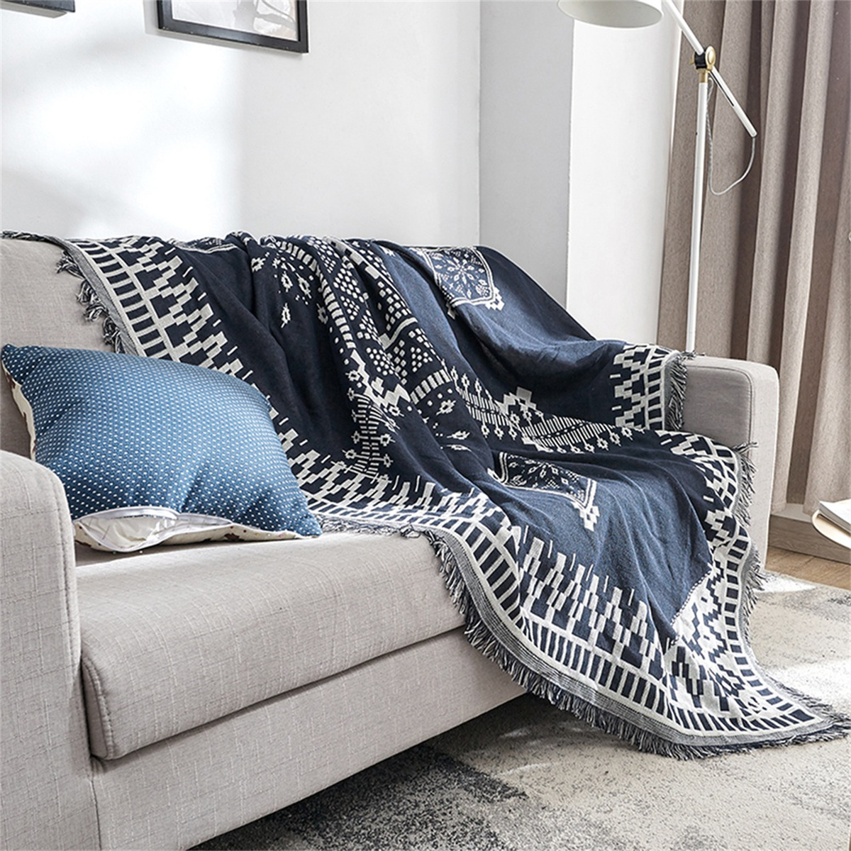 Eine marineblaue gemusterte Decke auf einem grauen Sofa mit blauem Kissen.