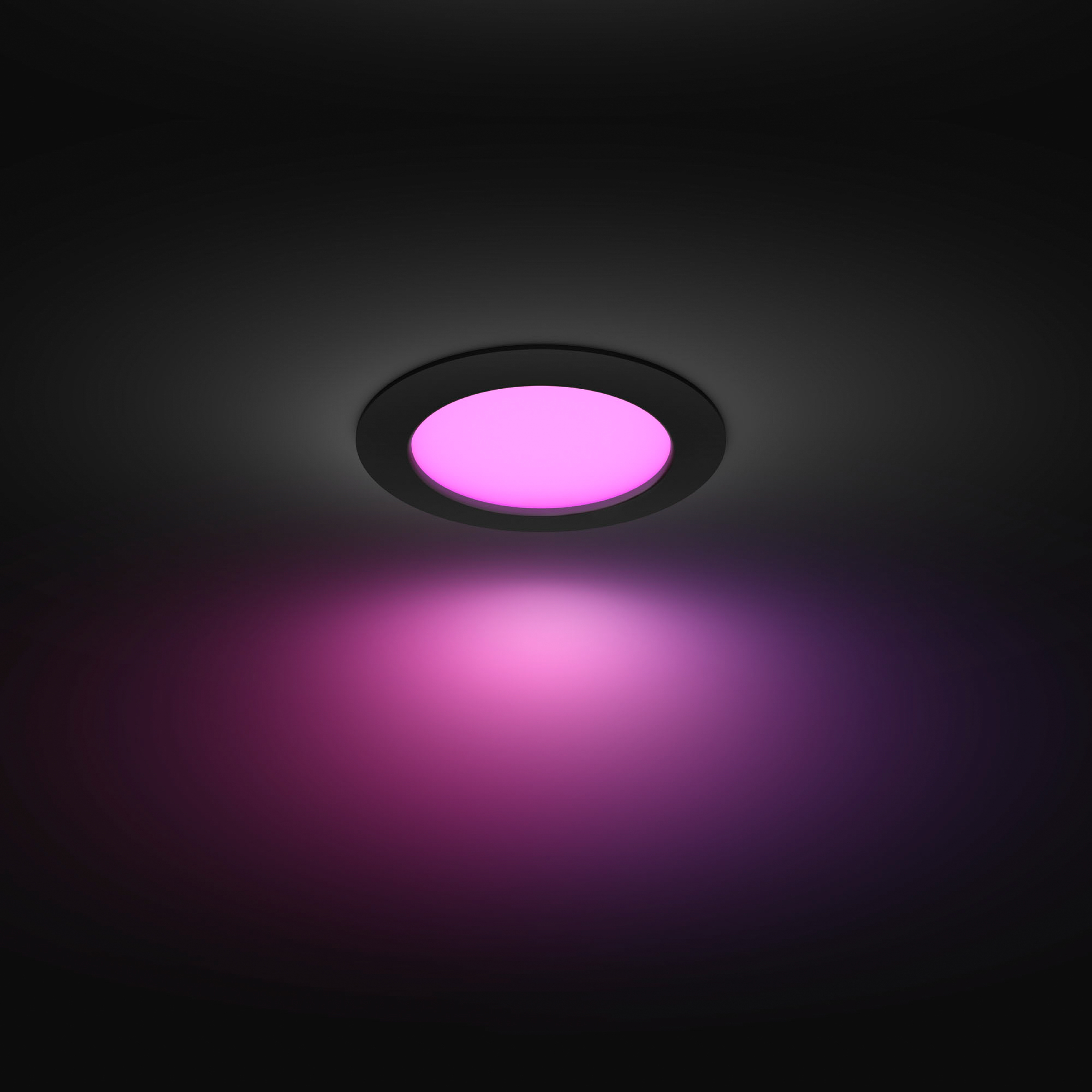 Plafonnier rond émettant une lumière rose. Cadre noir. Fond sombre.